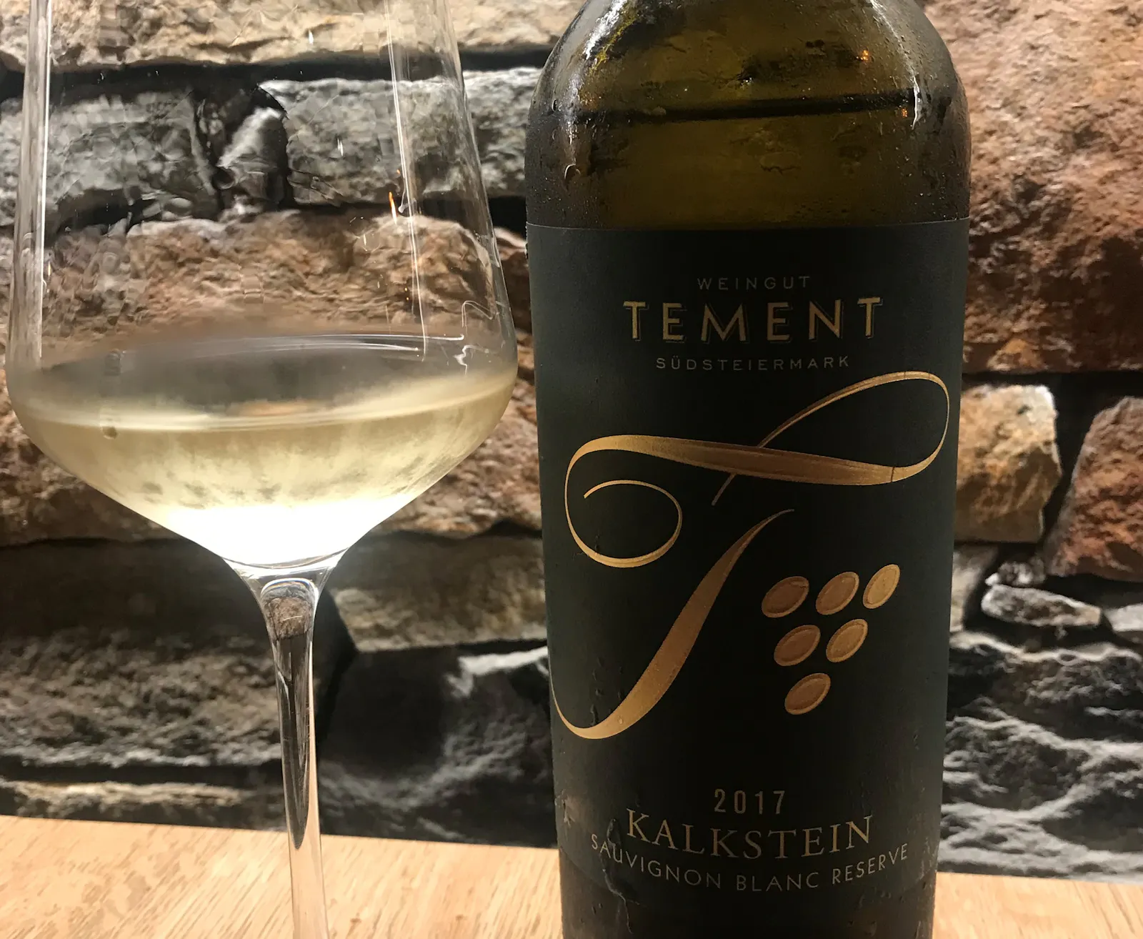 Ein Glas mit Weißwein und eine Weinflasche stehen im Restaurant auf einem Tisch.