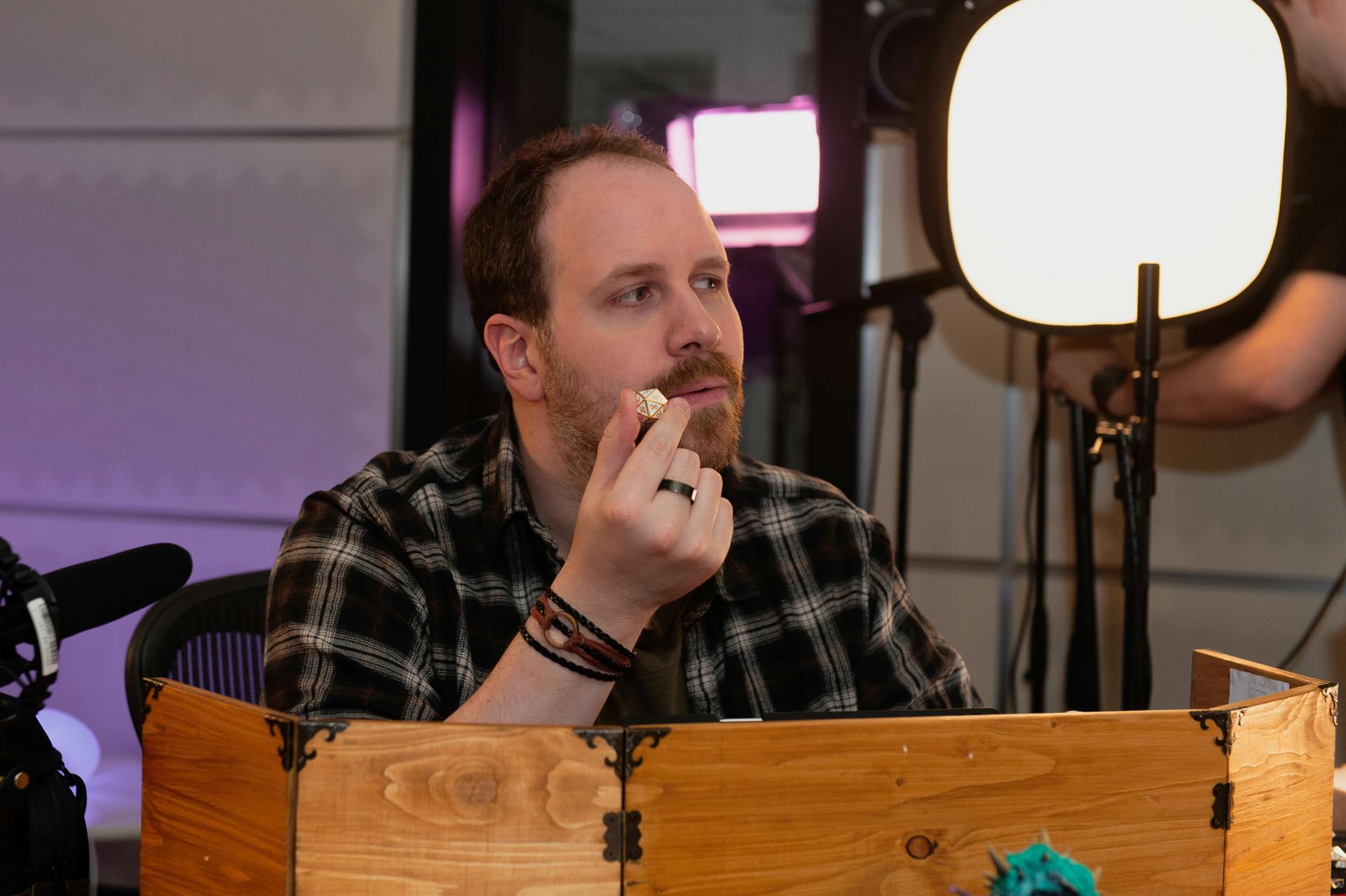 Alex hinter seinem Spielleiterschirm mit einem Würfel in der Hand