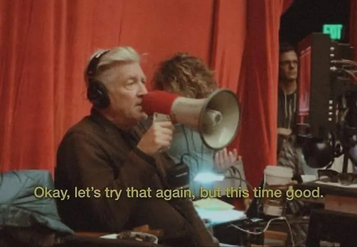 Auf dem Bild ist der Regiesseur David Lynch zu sehen. Er hält ein Megaphone in der Hand und ruft: "Okay, let's try that again, but this time good."