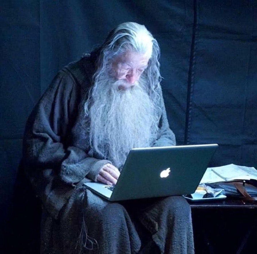 Ian McKellen in costume as Gandalf using a Macbook while relaxing on set of a Peter Jackson movie