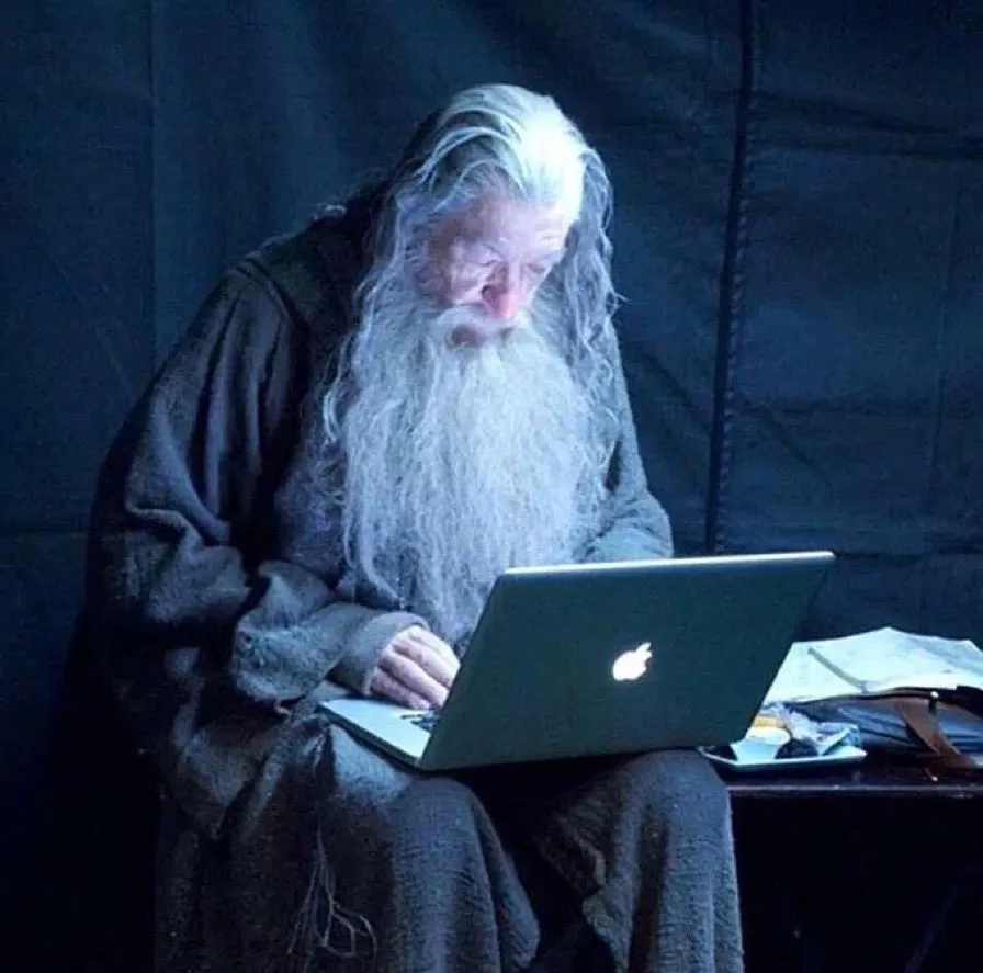 Ian McKellen in costume as Gandalf using a Macbook while relaxing on set of a Peter Jackson movie