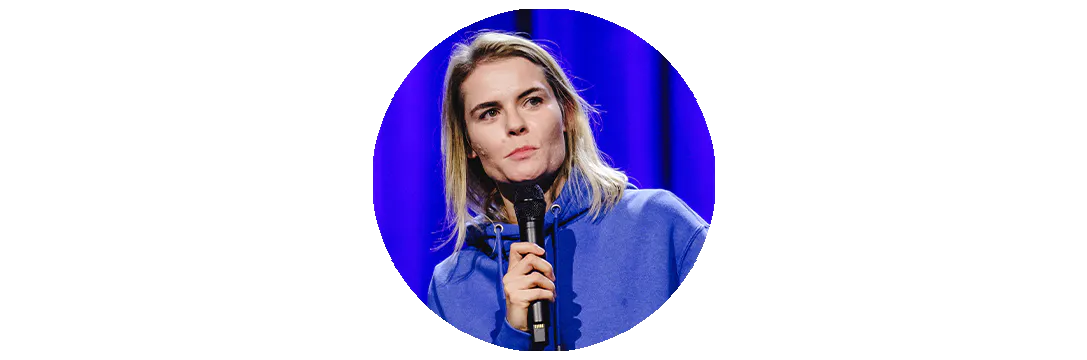 Hazel Brugger, die einen Kapuzenpulli trägt, auf einer Bühne steht und in ein Mikro spricht.