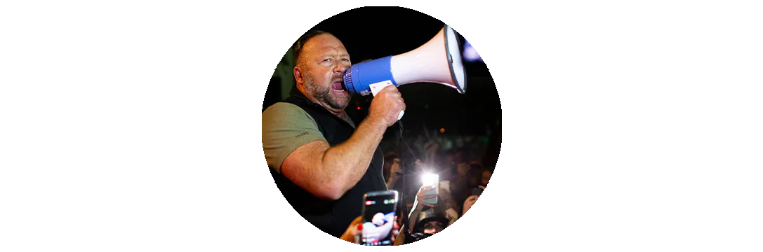 Alex Jones, der in ein Megafon schreit. Er ist umringt von Leuten.