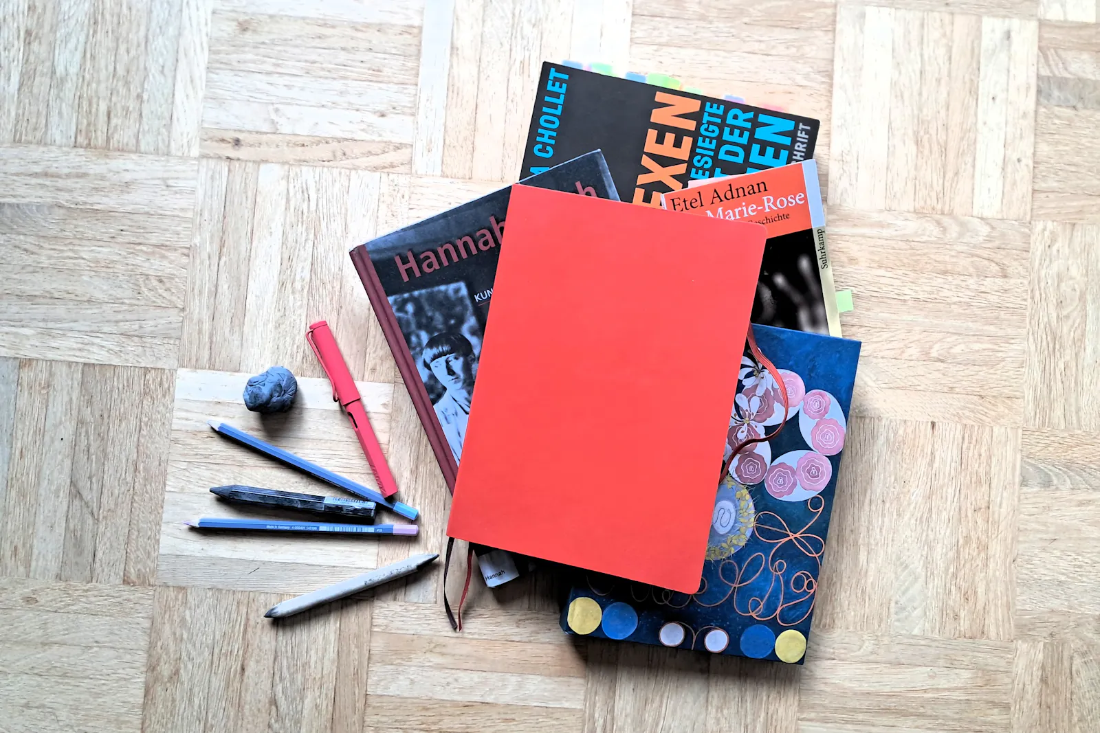 Verschiedene Bücher, Stifte und Notizbücher liegen auf dem Boden.