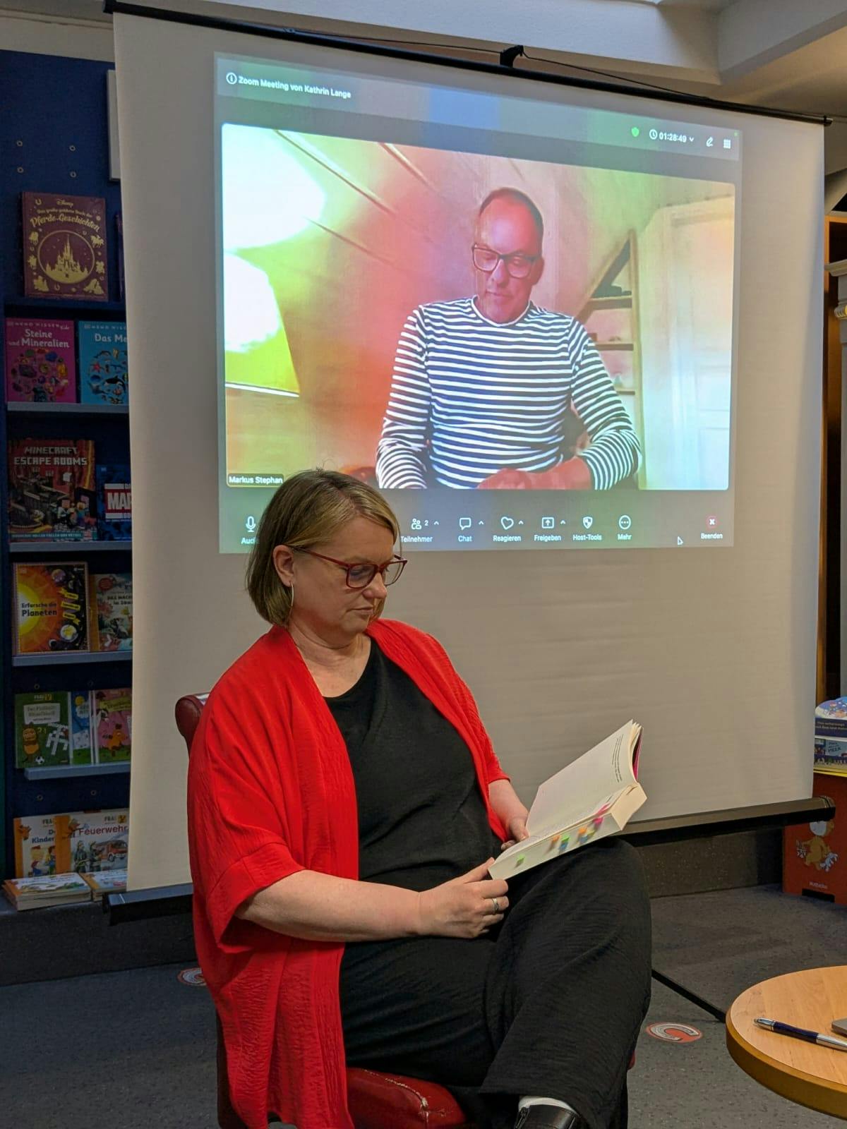 Katja vorn lesend, Markus per Videoschalte im Hintergrund