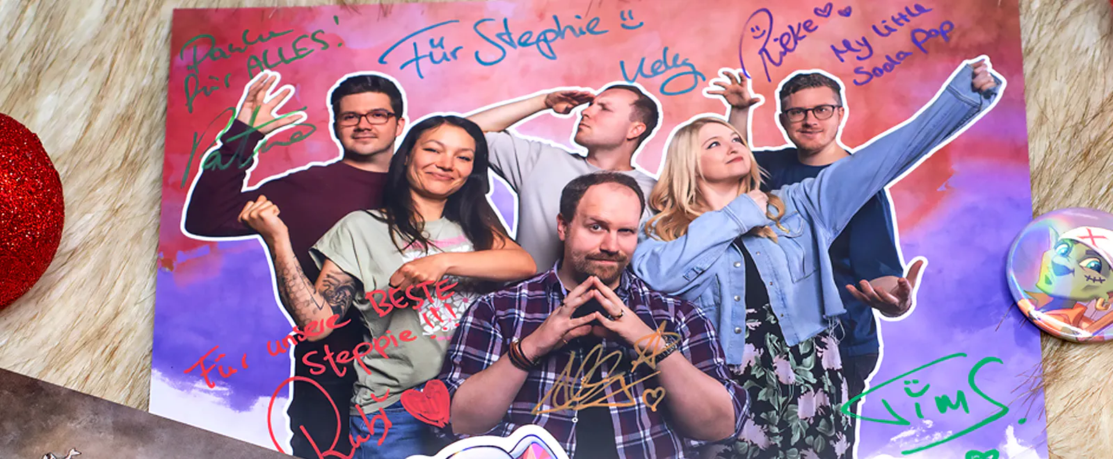 Eine Autogrammkarte der Dice Actors mit Patze, Rubi, Kelly, Alex, Rieke und Tim, die passend zu ihren Rollen der Hüter posieren.