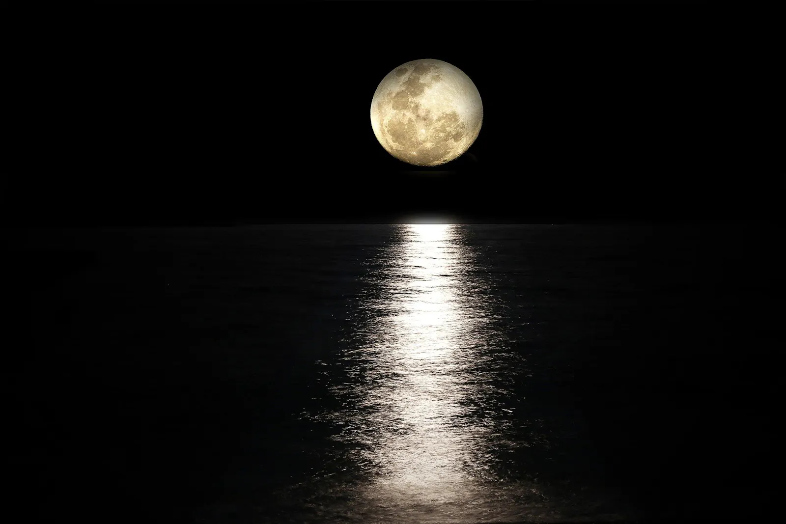 Vollmond über einem dunklen Gewässer.