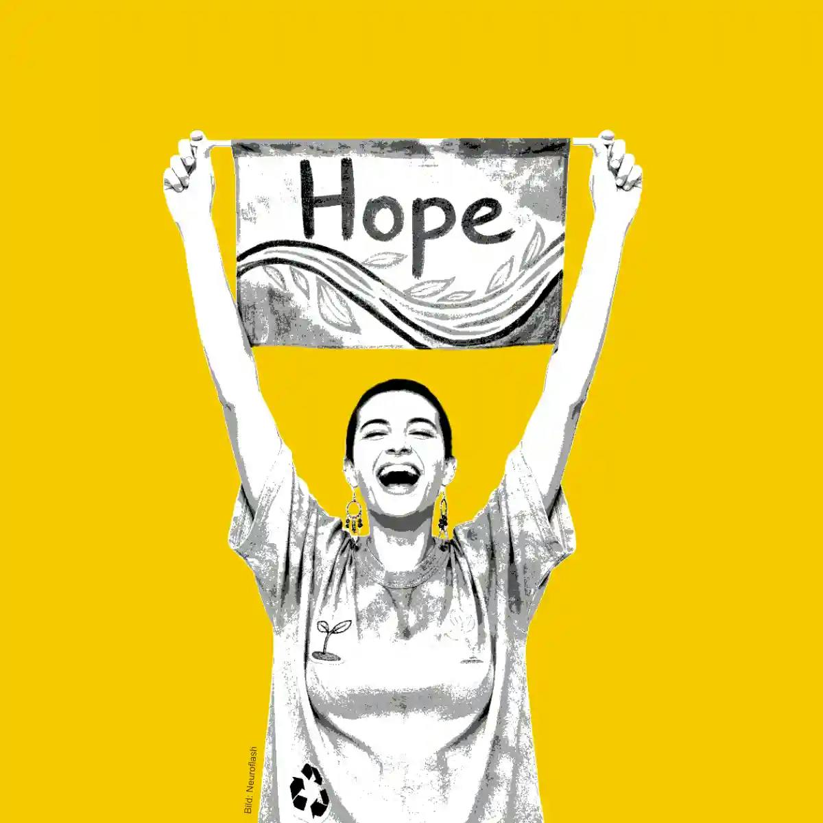 [Eine Frau trägt ein Banner mit der Auschrift "Hope"]
