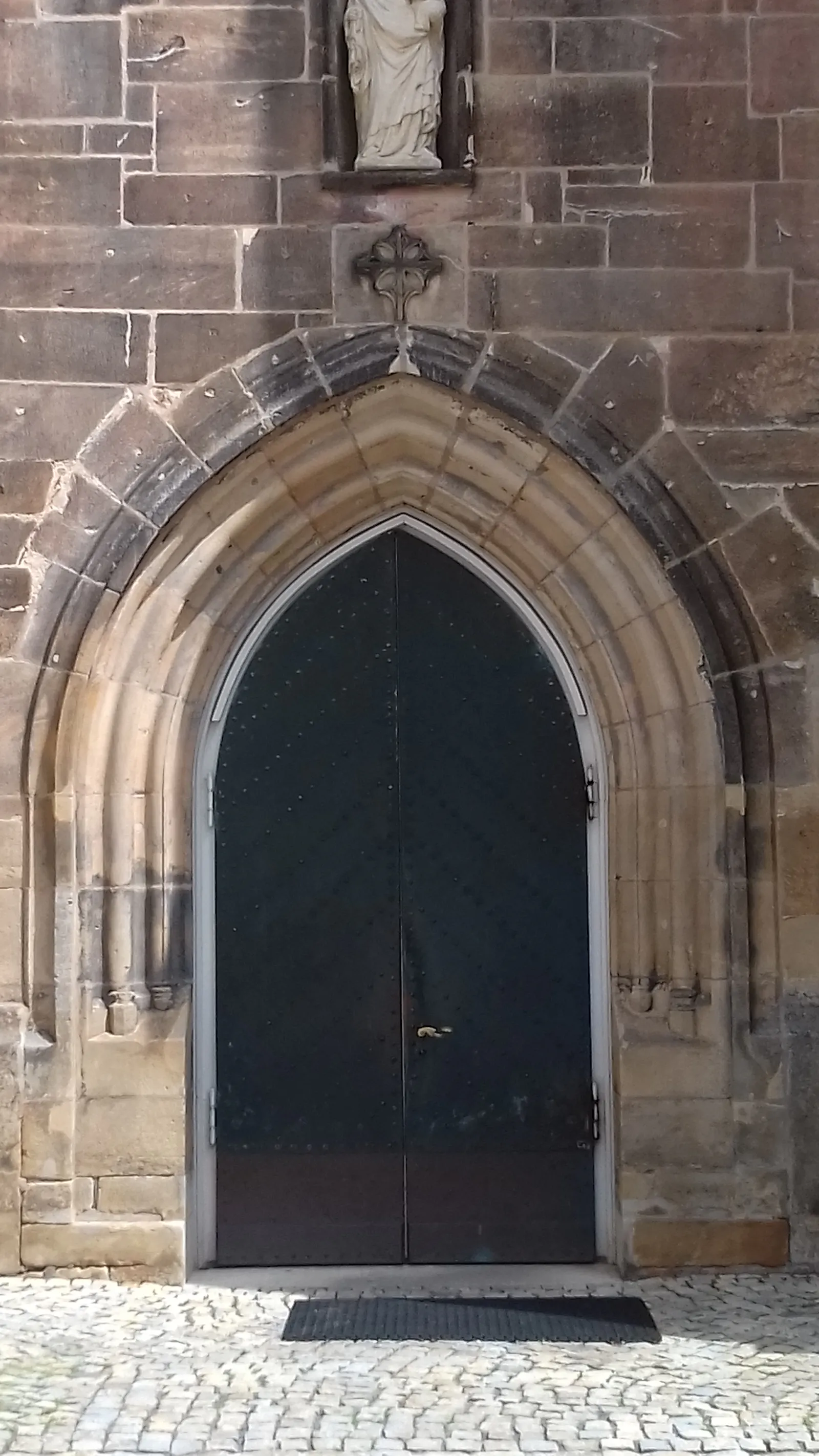 Eine dunkle Kirchentür im steinernen Gebäude.