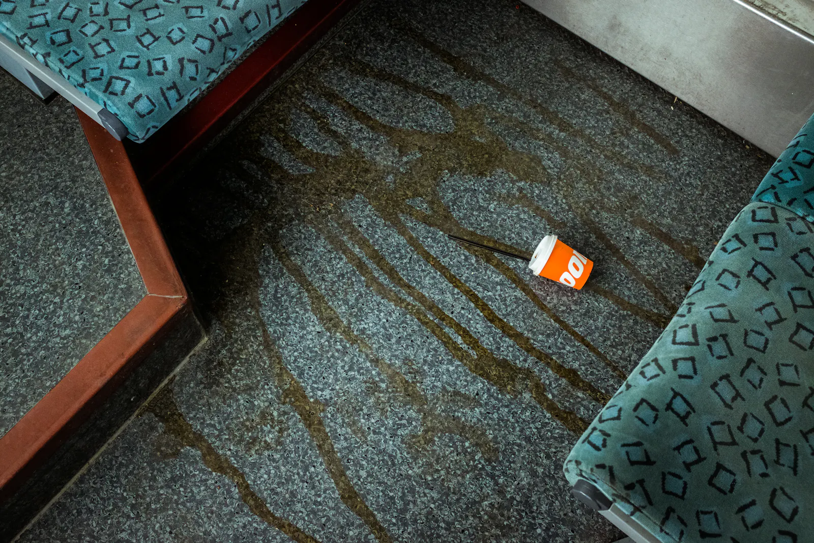 Ein Kaffeebecher, der auf dem Boden liegt und der verschüttete Kaffee.