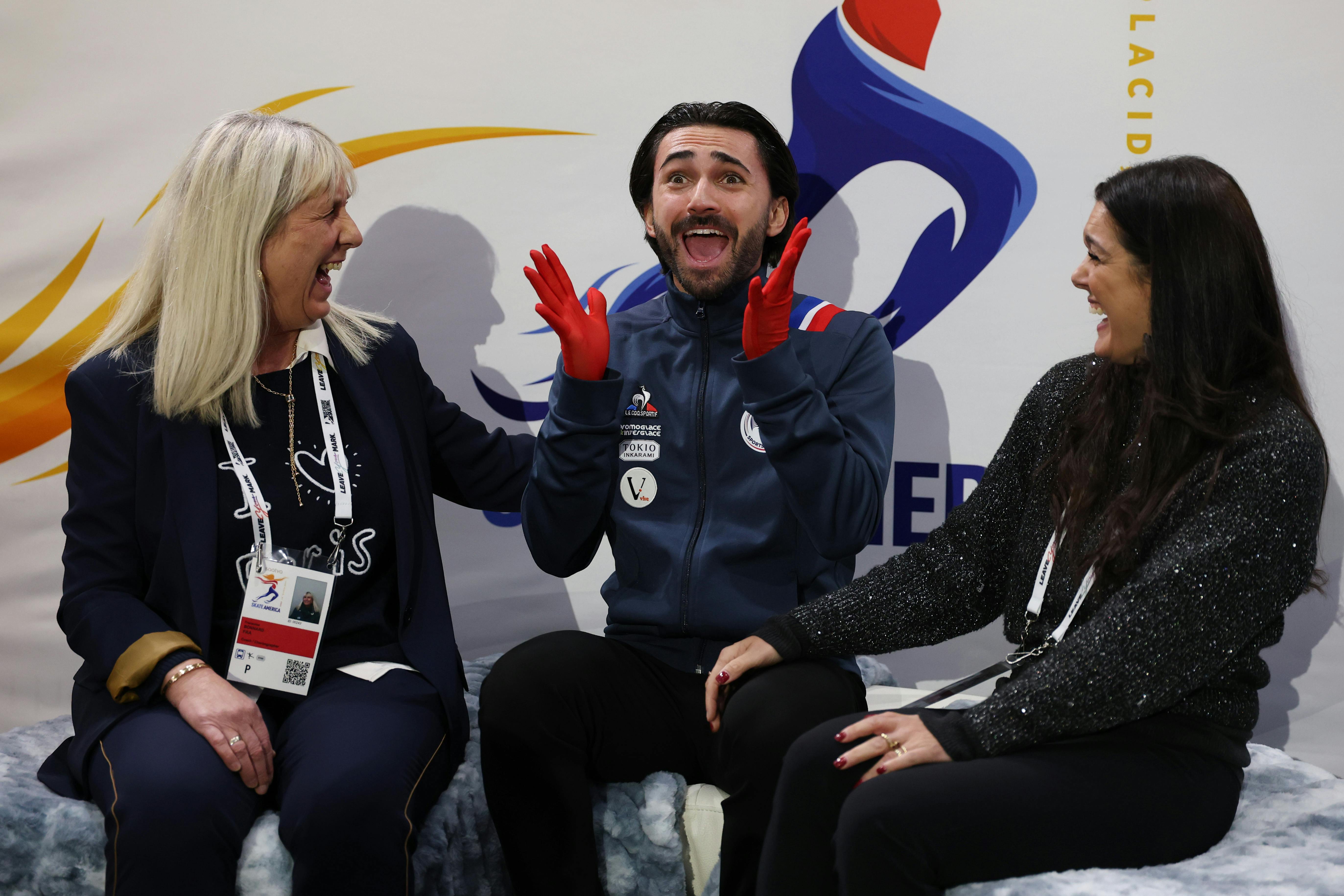 Kévin Aymoz und seine Trainerinnen Francoise Bonnard (links) und Silvia Fontana freuen sich über die Bewertung bei Skate America