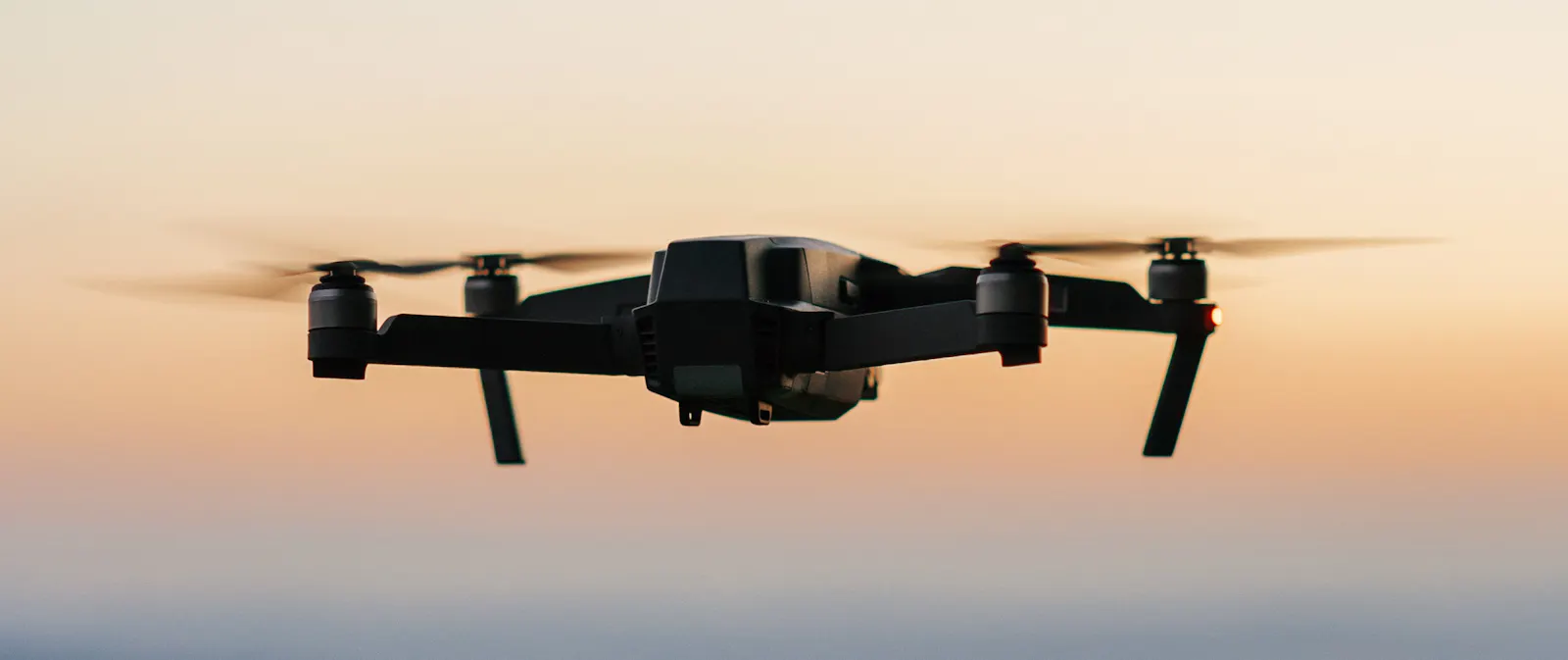 Auf dem Bild ist eine Drohne im Flug vor dem Abendhimmel zu sehen.