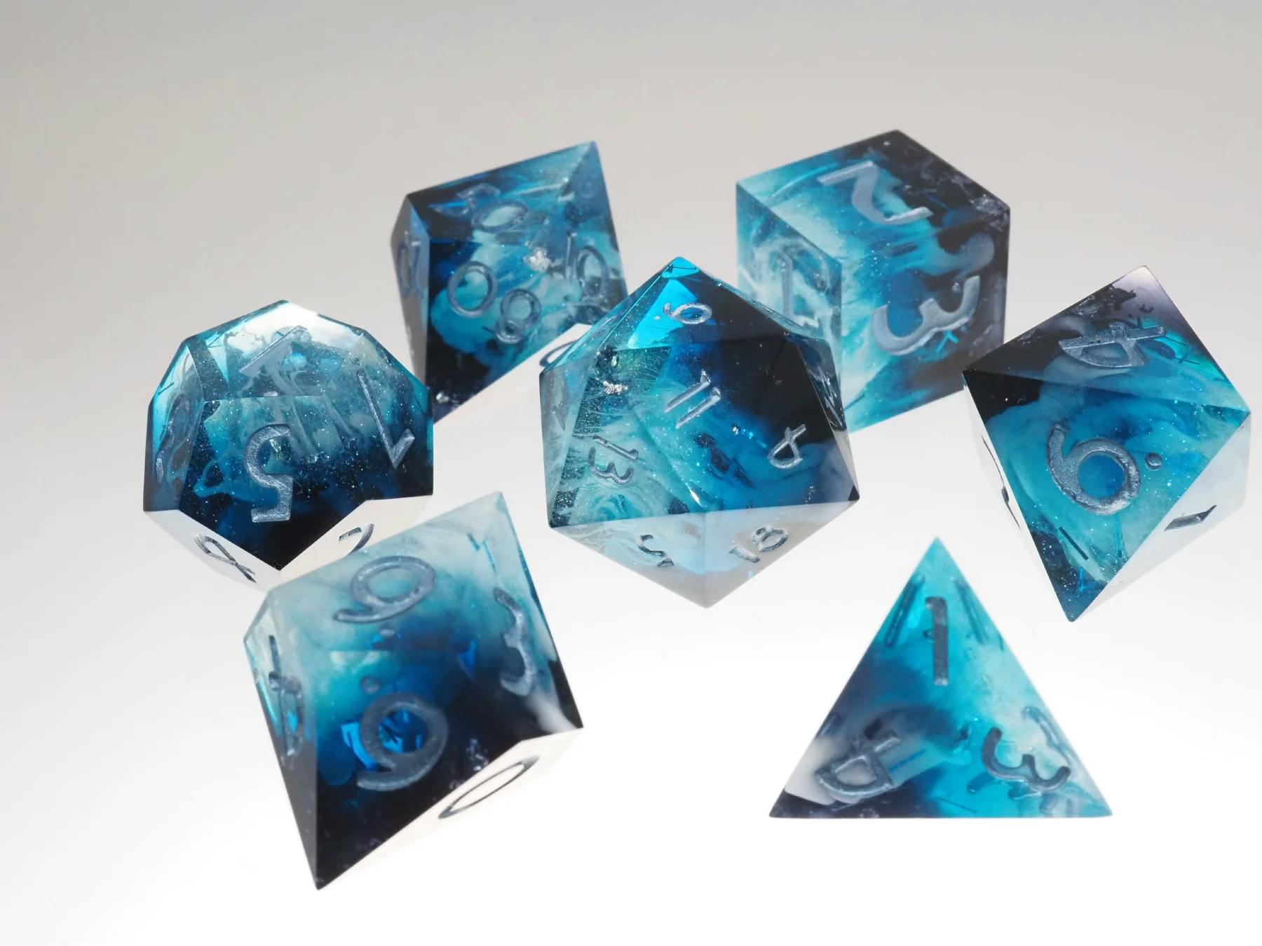 Das Set "Geheimnisvoller Gletscher" von CITDB ist ein Set aus blau-transparenten, polyedrischen Würfeln mit wirbelnden, eisartigen Einschlüssen und silbernen Zahlen.