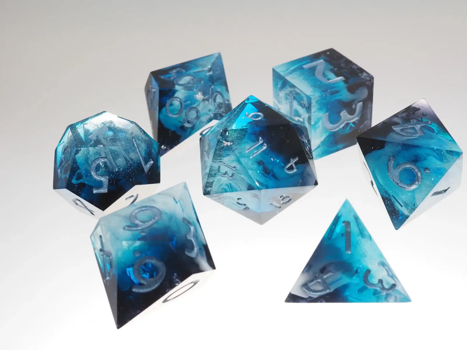 Das Set "Geheimnisvoller Gletscher" von CITDB ist ein Set aus blau-transparenten, polyedrischen Würfeln mit wirbelnden, eisartigen Einschlüssen und silbernen Zahlen.
