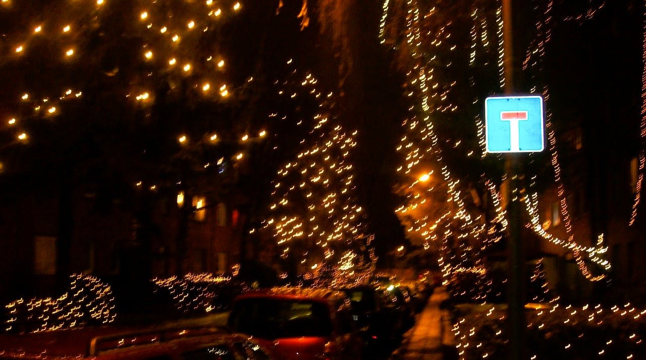 Eine Straße bei Nacht wird von vielen kleinen Lichtern erleuchtet. Ein Schild, das eine Sackgasse anzeigt, reflektiert Licht.