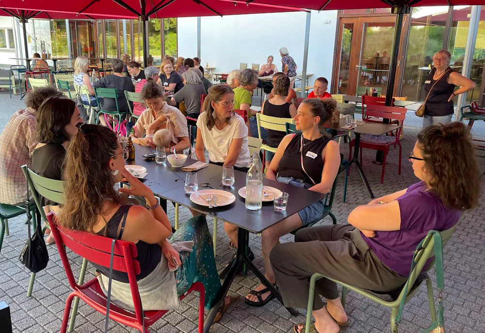 Eine Gruppe von Frauen sitzt in angeregtem Gespräch um einen Tisch im Freien.