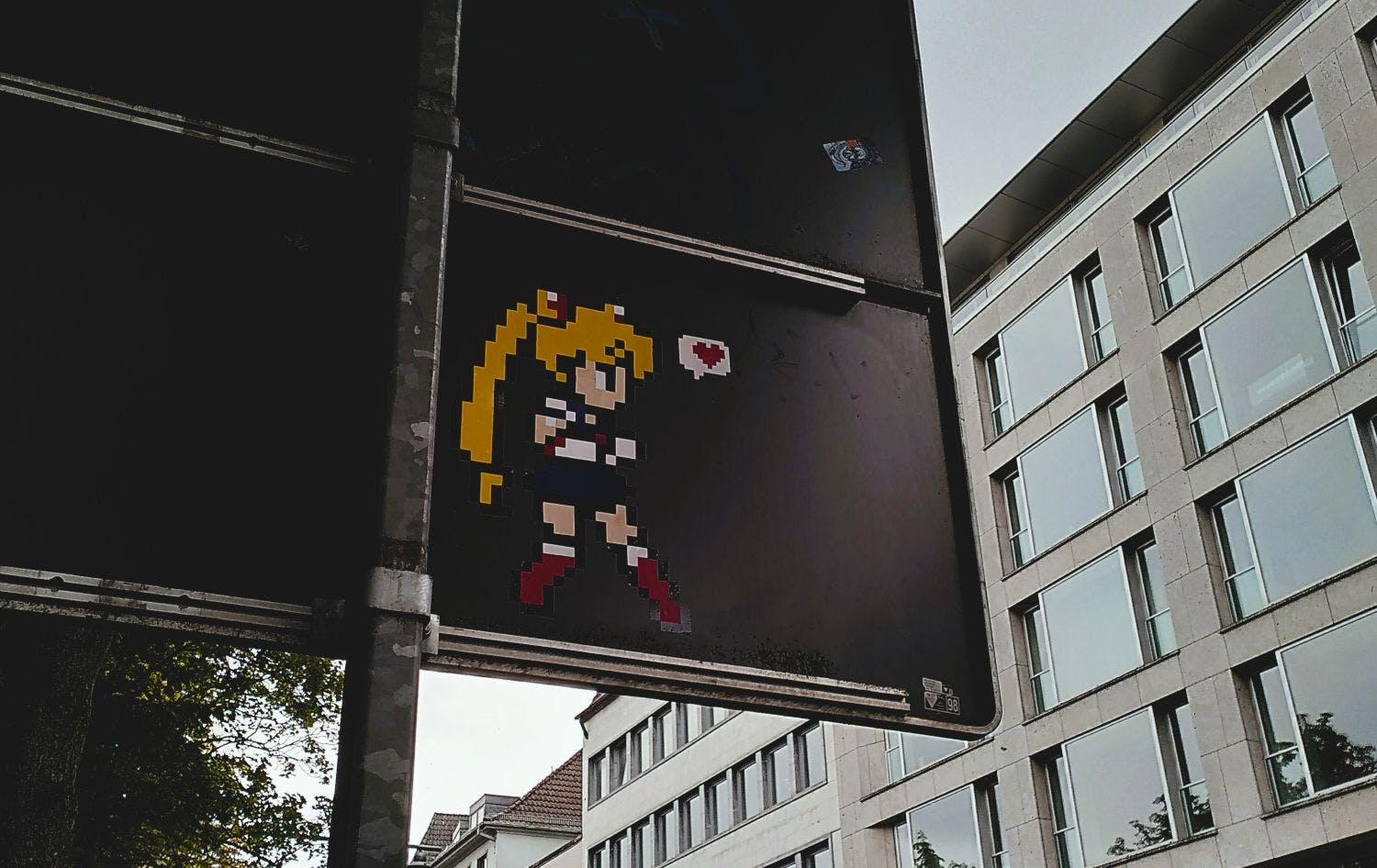Auf der Rückseite eines Straßenschildes ist eine verpixelte Figur "Sailor Moon" aufgebracht.