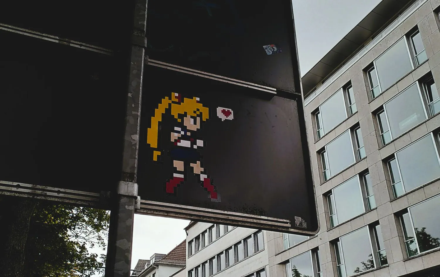 Auf der Rückseite eines Straßenschildes ist eine verpixelte Figur "Sailor Moon" aufgebracht.