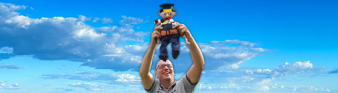 Lachender Mann hält eine Lokführerpuppe in die Höhe