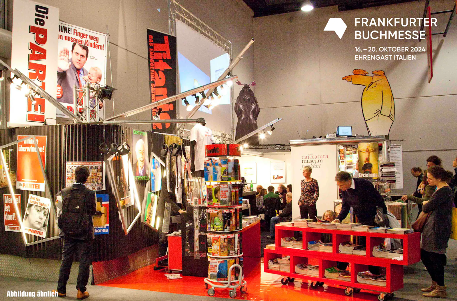 TITANIC-Buchmessestand. Besucher und Besucherinnen schauen sich den Stand an. An den Wänden hängen Poster mit bekannten TITANIC-Motiven.