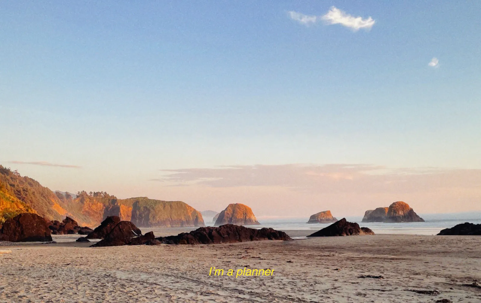 Ein Strand mit Felsen im Abendlicht, unten steht in gelber Schrift "I'm a planner"