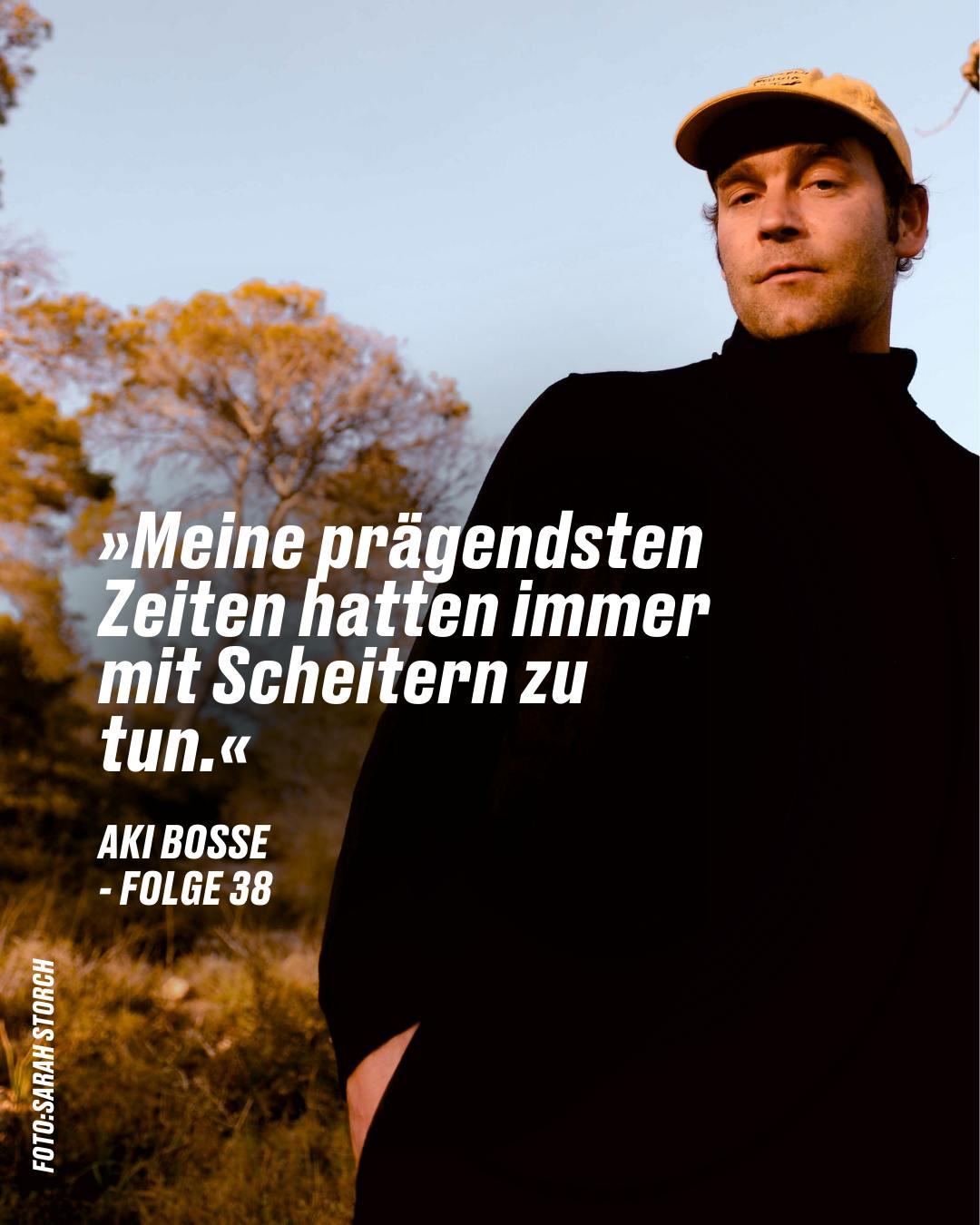 Aki Bosse in einem schwarzen Mantel und einer Kappe steht vor einem Hintergrund von Bäumen. Über ihm steht ein Zitat: "Meine prägendsten Zeiten hatten immer mit Scheitern zu tun." - Folge 38. Fotograf: Sami Storch.