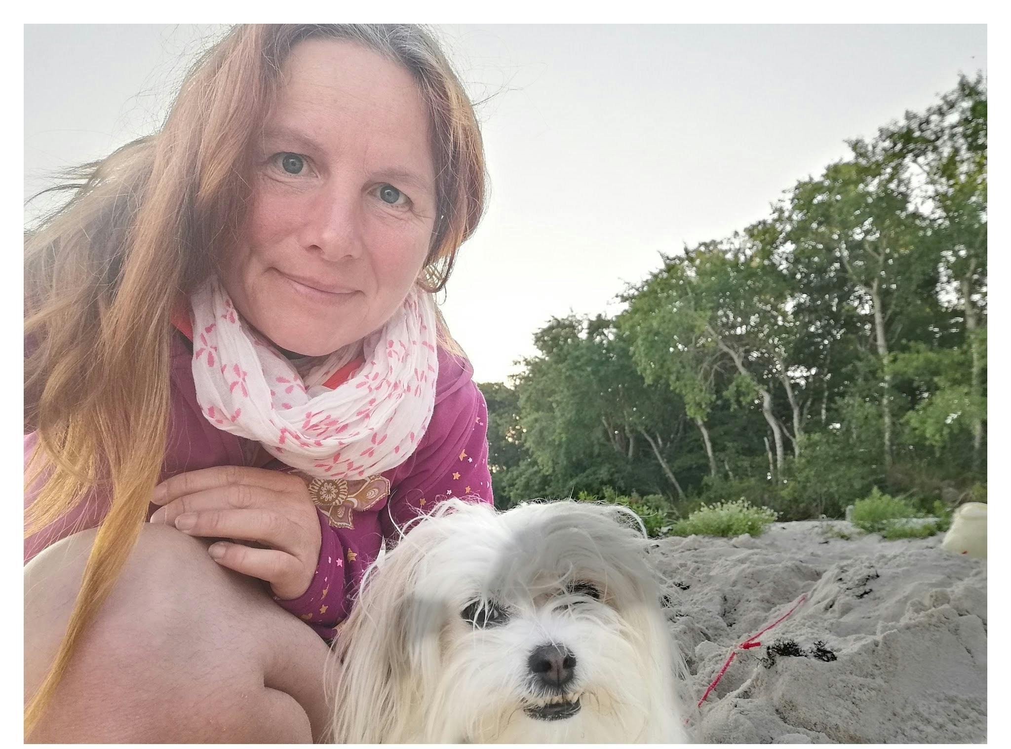 Ich sitze mit meiner Hündin am Strand.