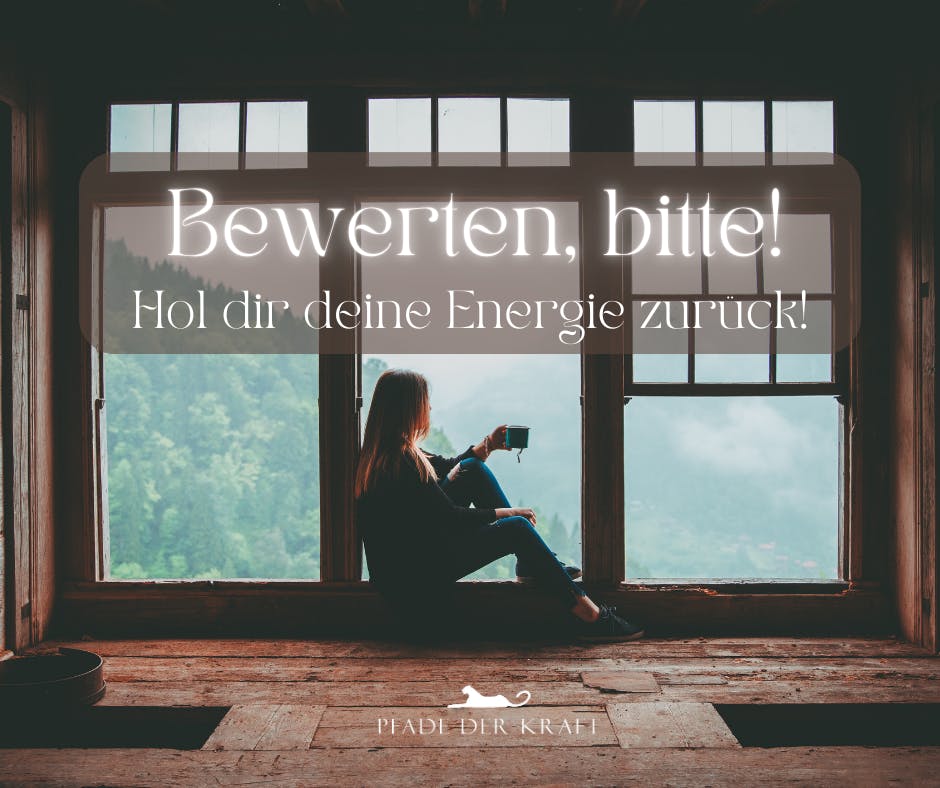 Eine blonde langaaharige Frau sitzt an einem großen Fenster in entspannter Haltung. Sie ist von der Seite zu sehen und hat eine Tasse in der Hand. Das Fenster ist bodentief und der Ausblick ist auf eine weite grüne bergige Landschaft.
