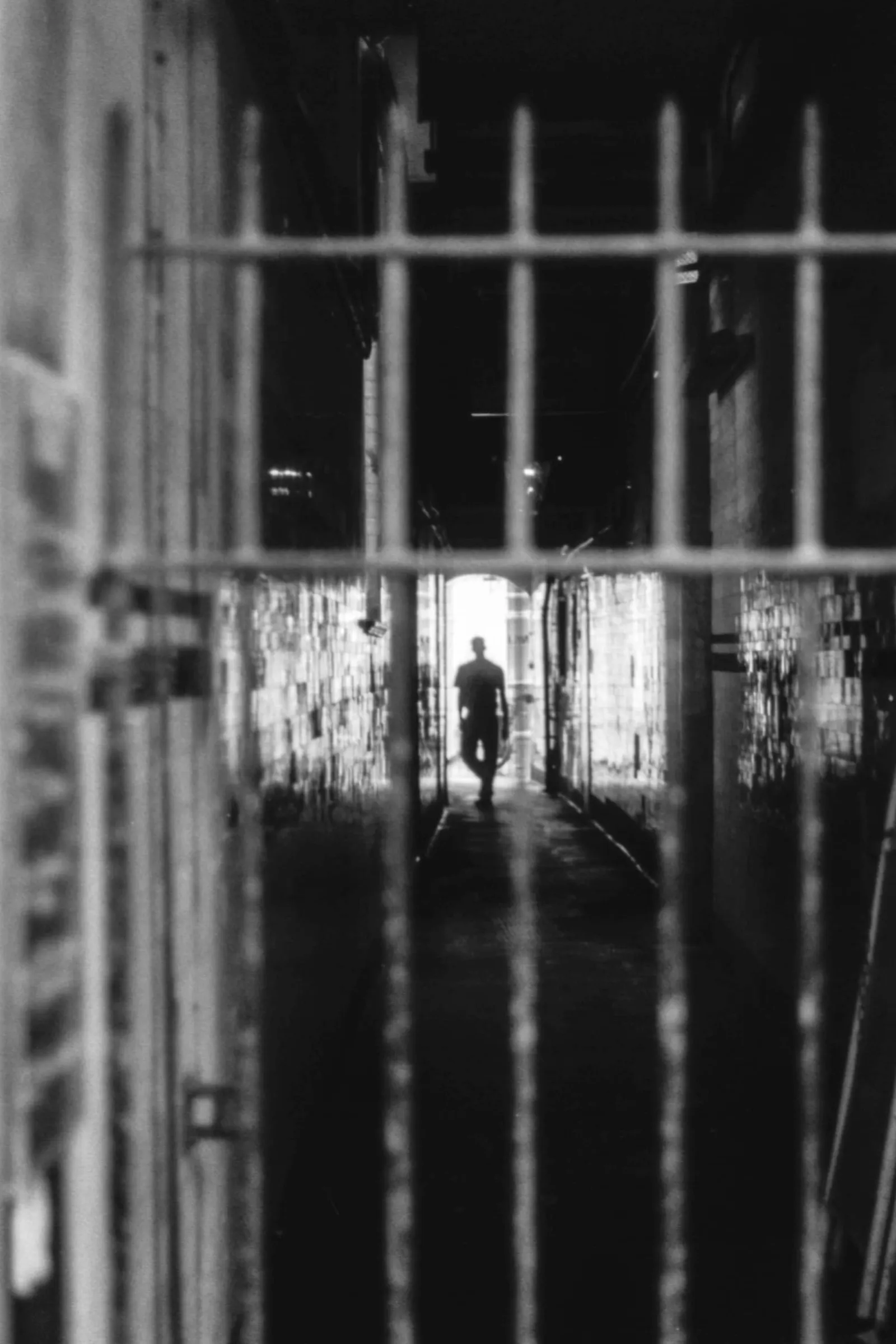 Between the steel bars, we see the silhouette of a man approaching.