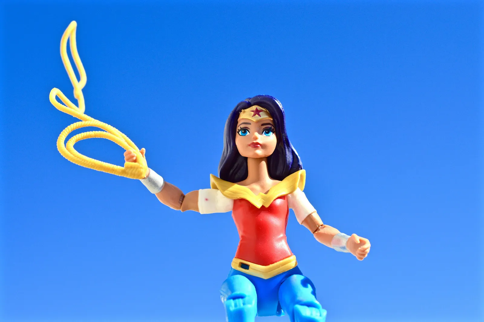 Eine Spielfigur von Wonder-Women, das Lasso schwingend vor himmelblauem Hintergrund