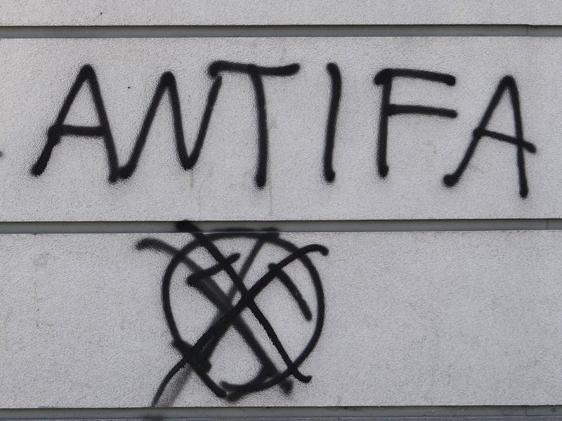 Antifa Graffiti, schwarz auf grauer Wand, darunter ein durchgestrichenes Hakenkreuz.https://www.flickr.com/photos/adam_jones/