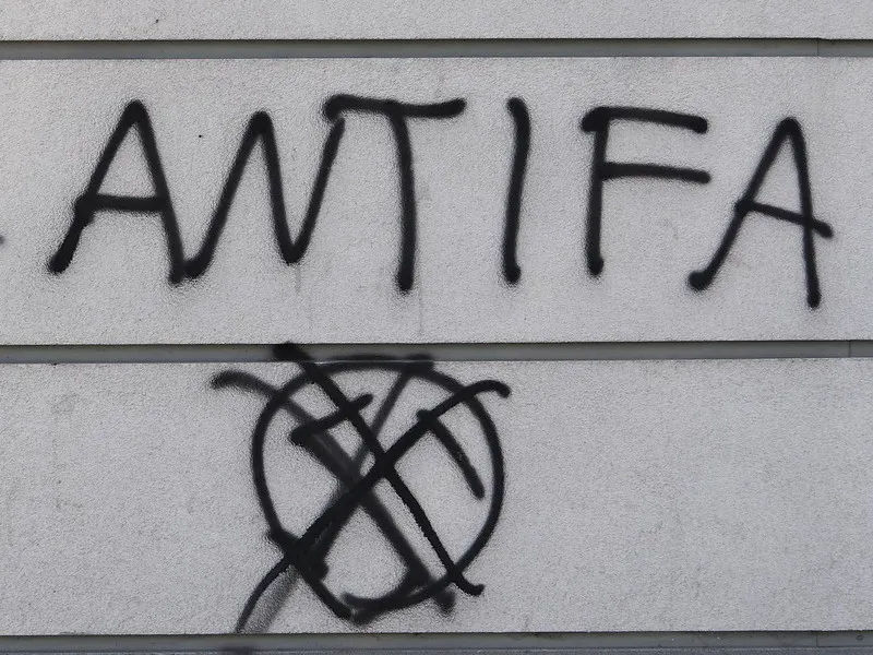 Antifa Graffiti, schwarz auf grauer Wand, darunter ein durchgestrichenes Hakenkreuz.https://www.flickr.com/photos/adam_jones/