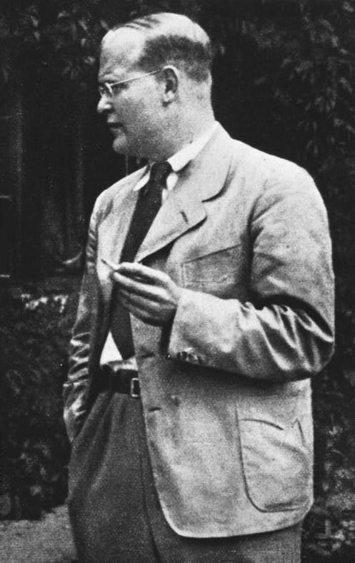Dietrich Bonnhoeffer, schwarzweiß, Anzug, Krawatte, Zigarette, blickt nach links im Gespräch.