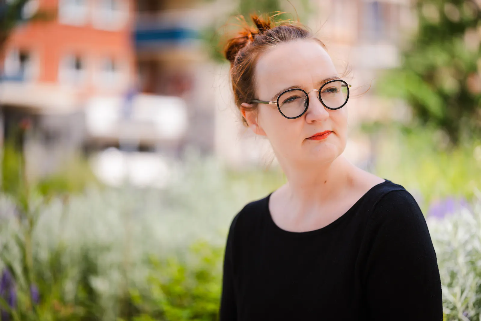 Insa van den Berg, Frau mit roten Haaren und Brille, kneift die Augen zusammen und schaut in die Ferne.