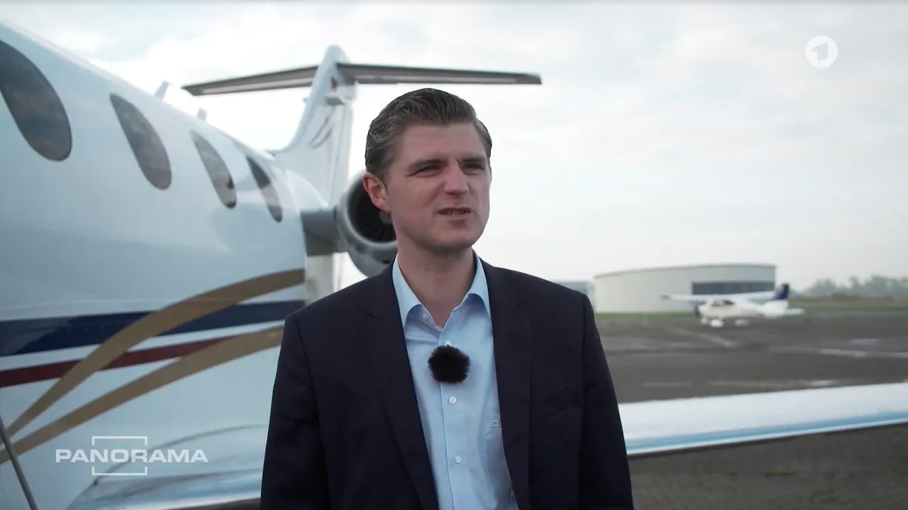 Verleger Julien Backhaus vor einem Privatjet - Symbolbild für die extreme soziale Ungleichheit im Zusammenhang mit der Klimakrise.