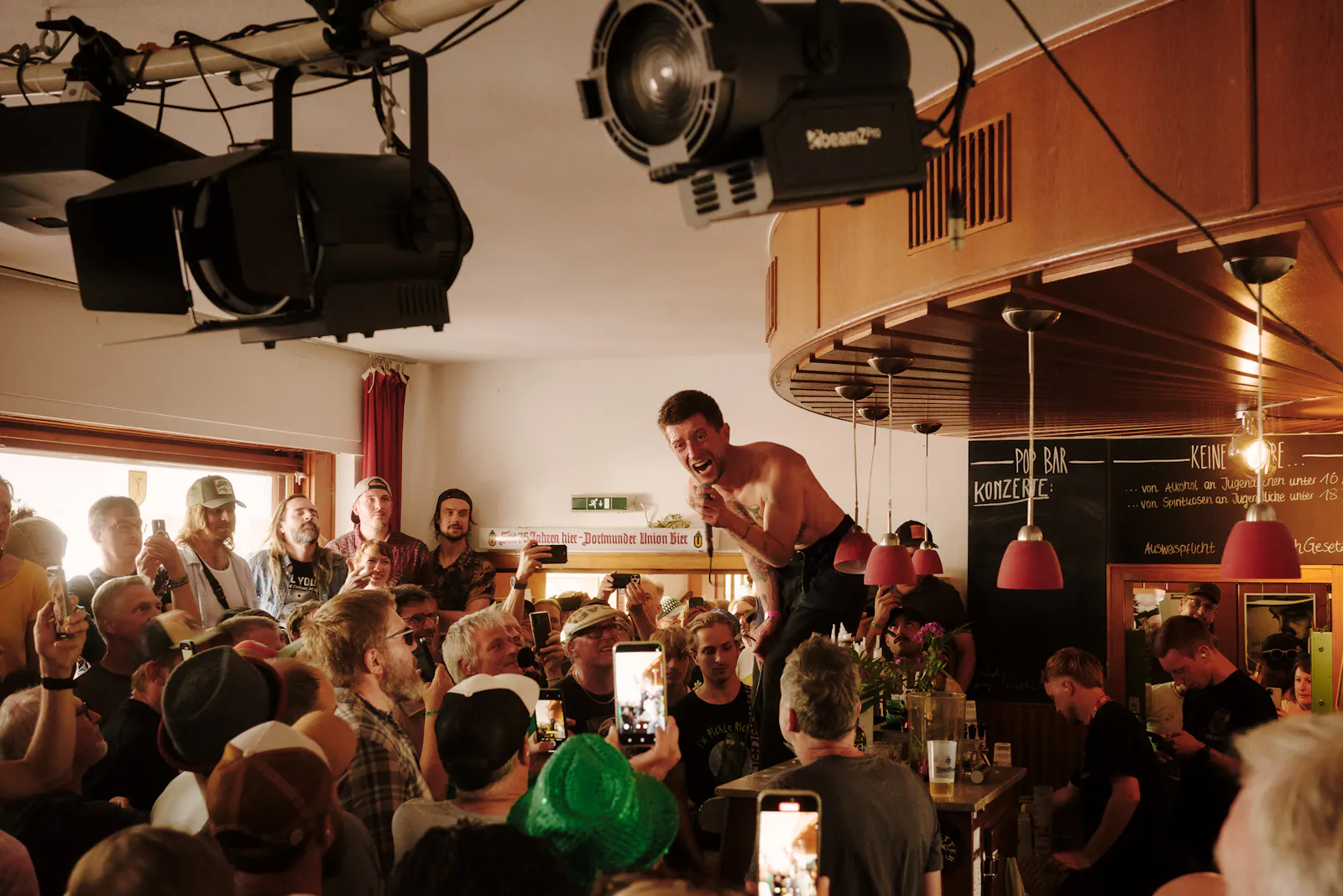 Die Band Heavy Lungs tritt in einer kleinen Bar beim Haldern Pop Festival auf, der Sänger steht auf der Theke, umringt von einem dicht gedrängten Publikum.