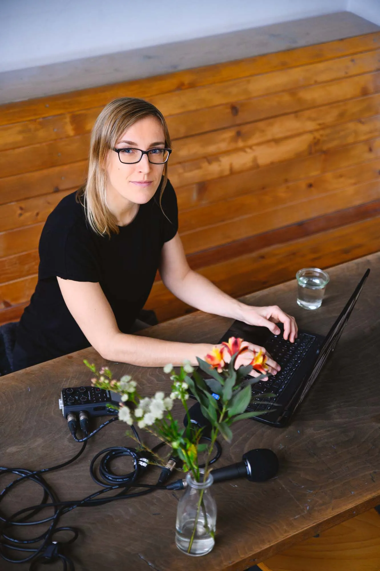 Juliane aus der Vogelperspektive am Laptop mit Mikro und einer Blumenvase