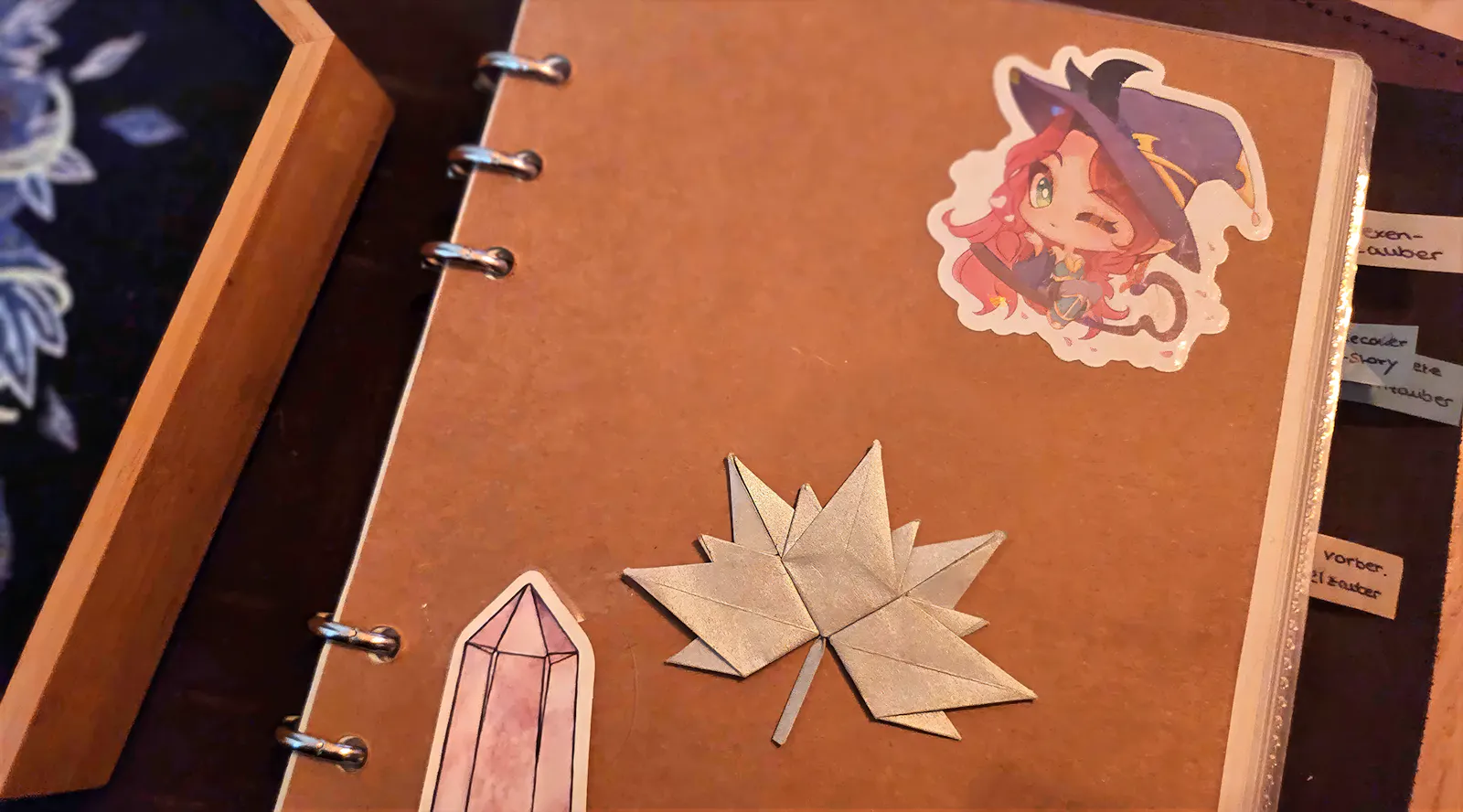 Deckblatt eines Büchleins mit Stickern von Elaynie, Silberblatt und Obelisk