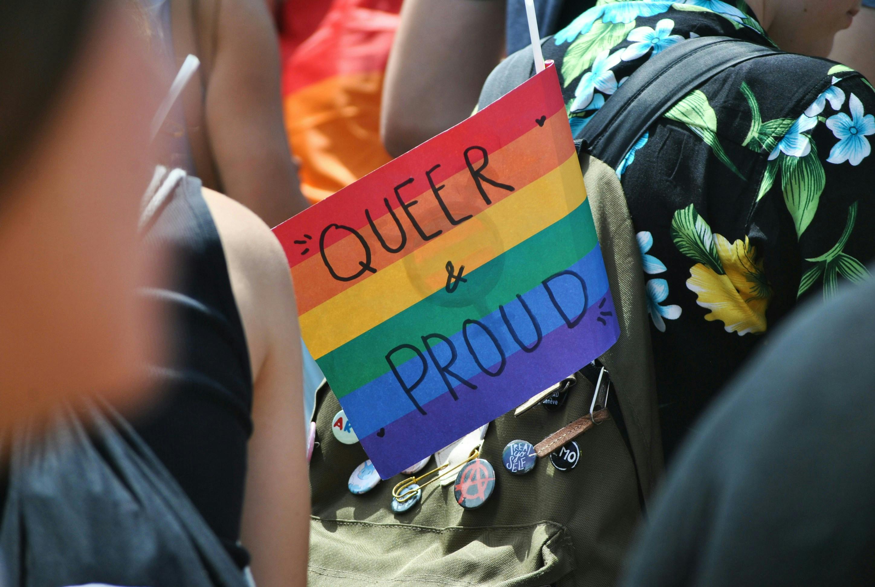 Foto von einer Demo, in der Bildmitte eine Flagge in Regenbogenfarben auf der Steht: Queer & Proud"