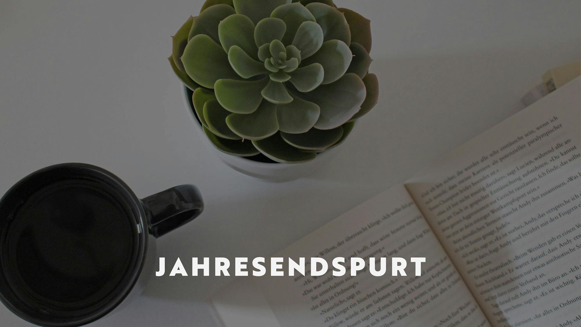 Ein aufgeschlagenes Buch neben dem eine Tasse mit Tee und eine Sukkulente stehen. Darauf der Titel des Beitrags: Jahresendspurt.