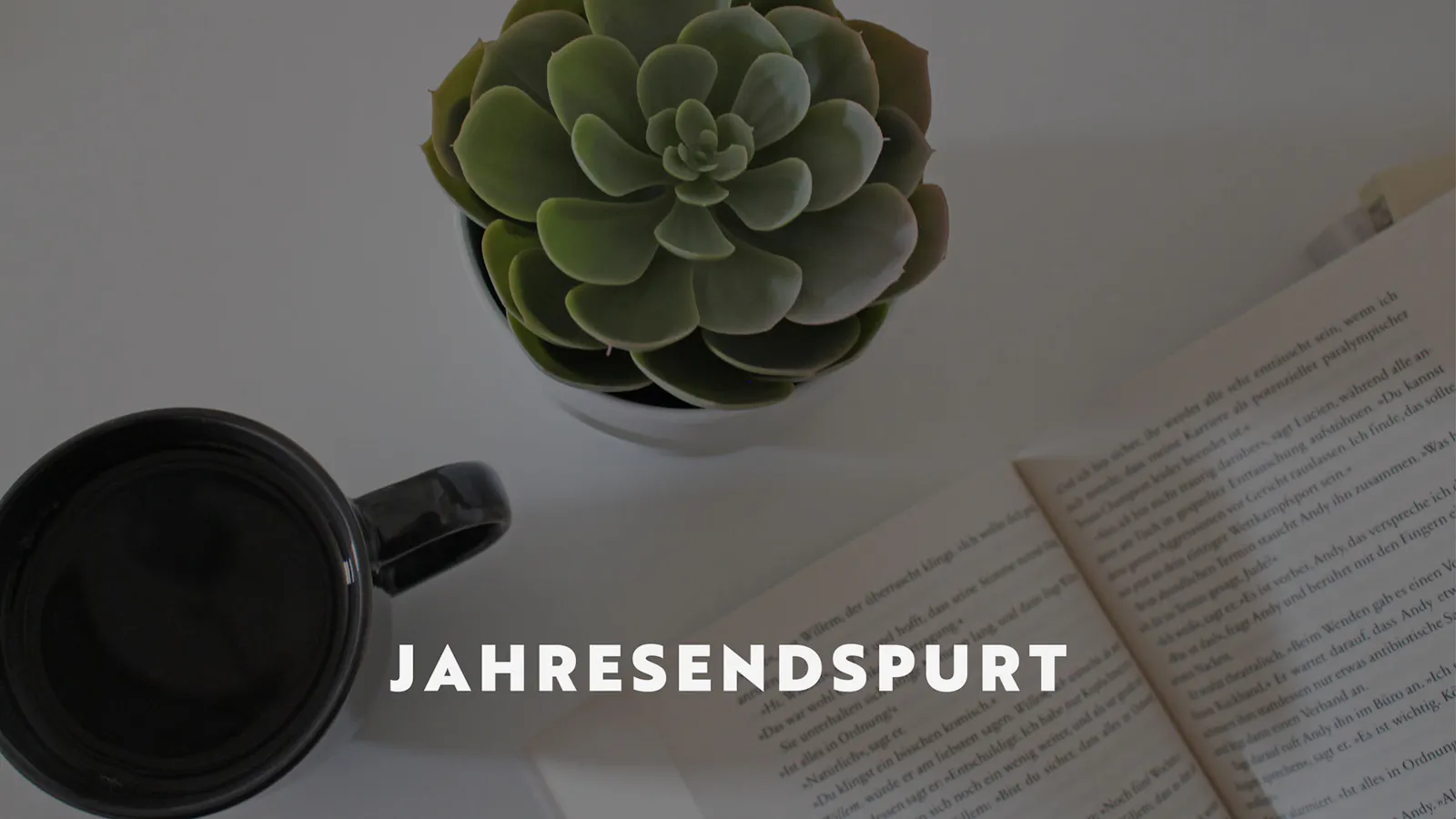 Ein aufgeschlagenes Buch neben dem eine Tasse mit Tee und eine Sukkulente stehen. Darauf der Titel des Beitrags: Jahresendspurt.