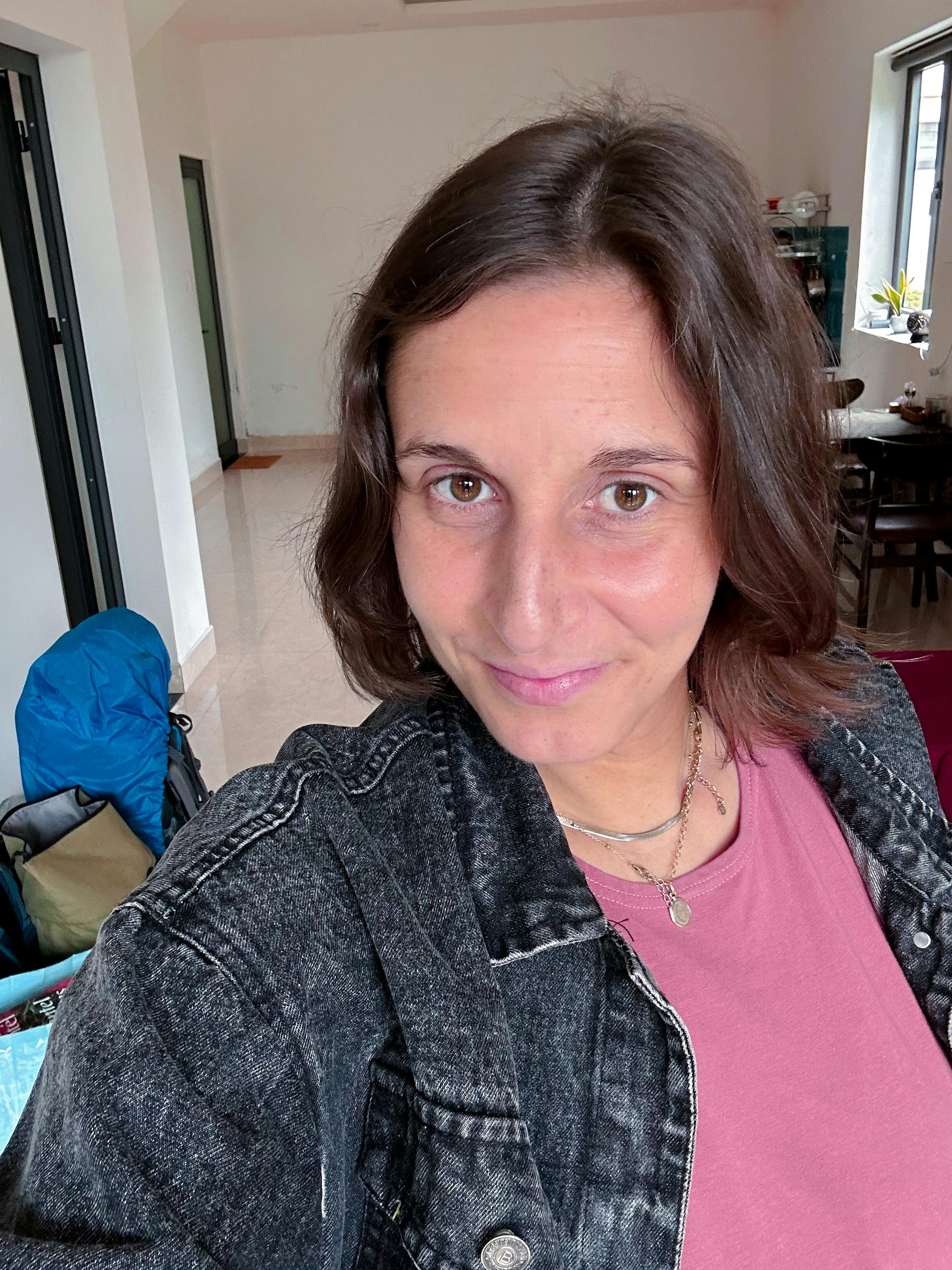 Josi blickt motiviert in die Kamera. Sie trägt eine schwarze Jeansjacke und ein rosa Top. Im Hintergrund ist ein Wohnzimmer zu sehen.