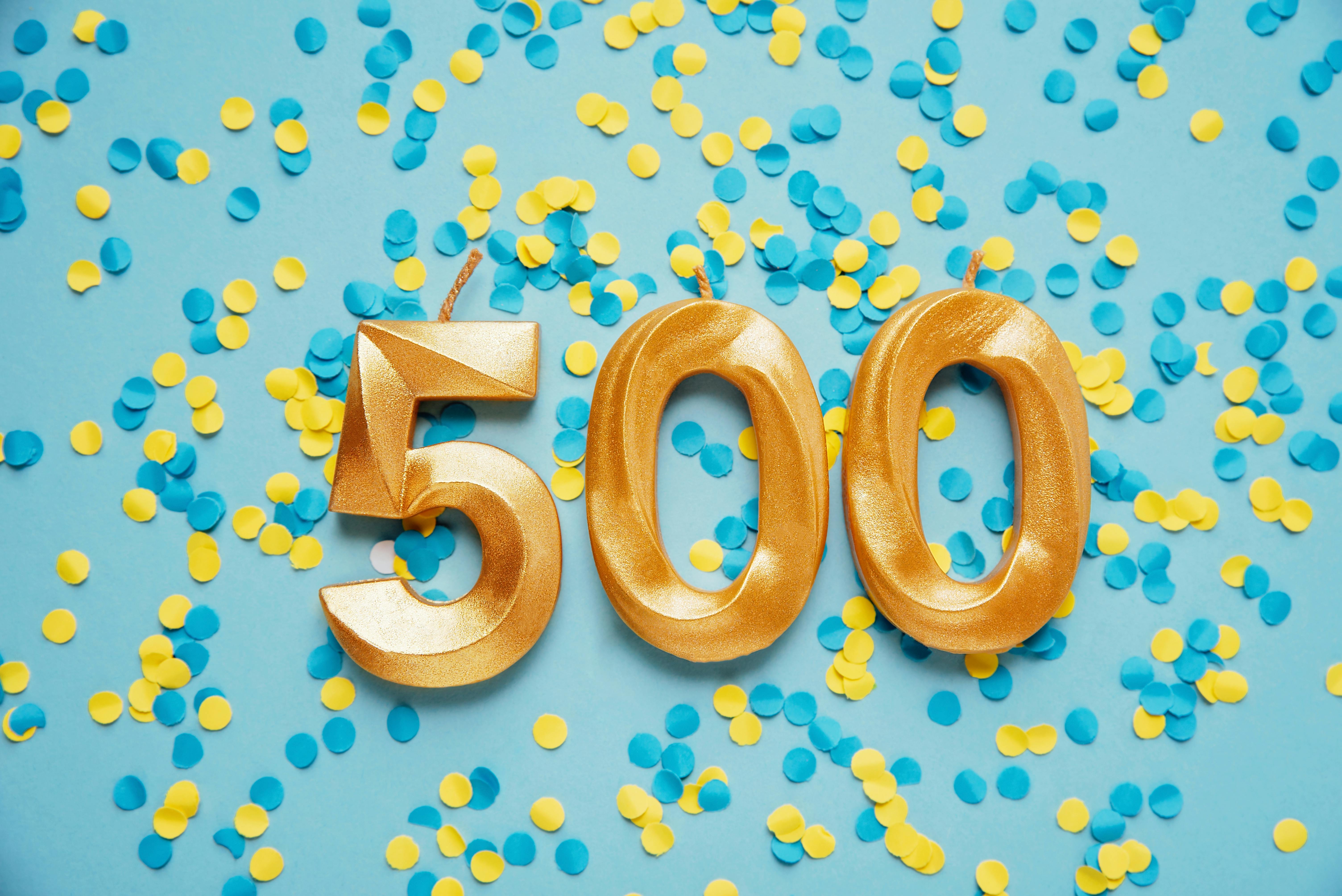 Die goldene Zahl 500 vor gelbem und blauen Konfetti.