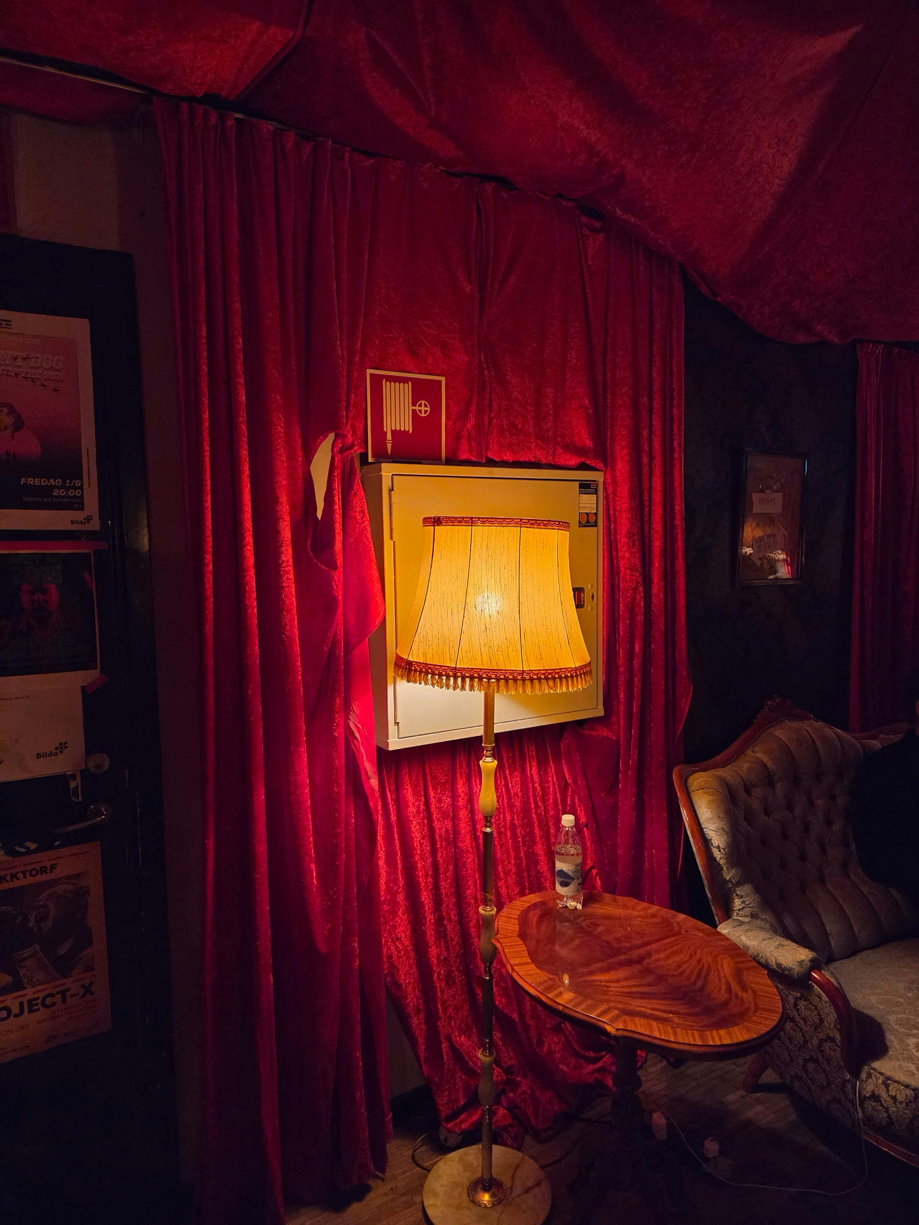 Roter Samtvorhang, Lampe, kleiner Tisch
