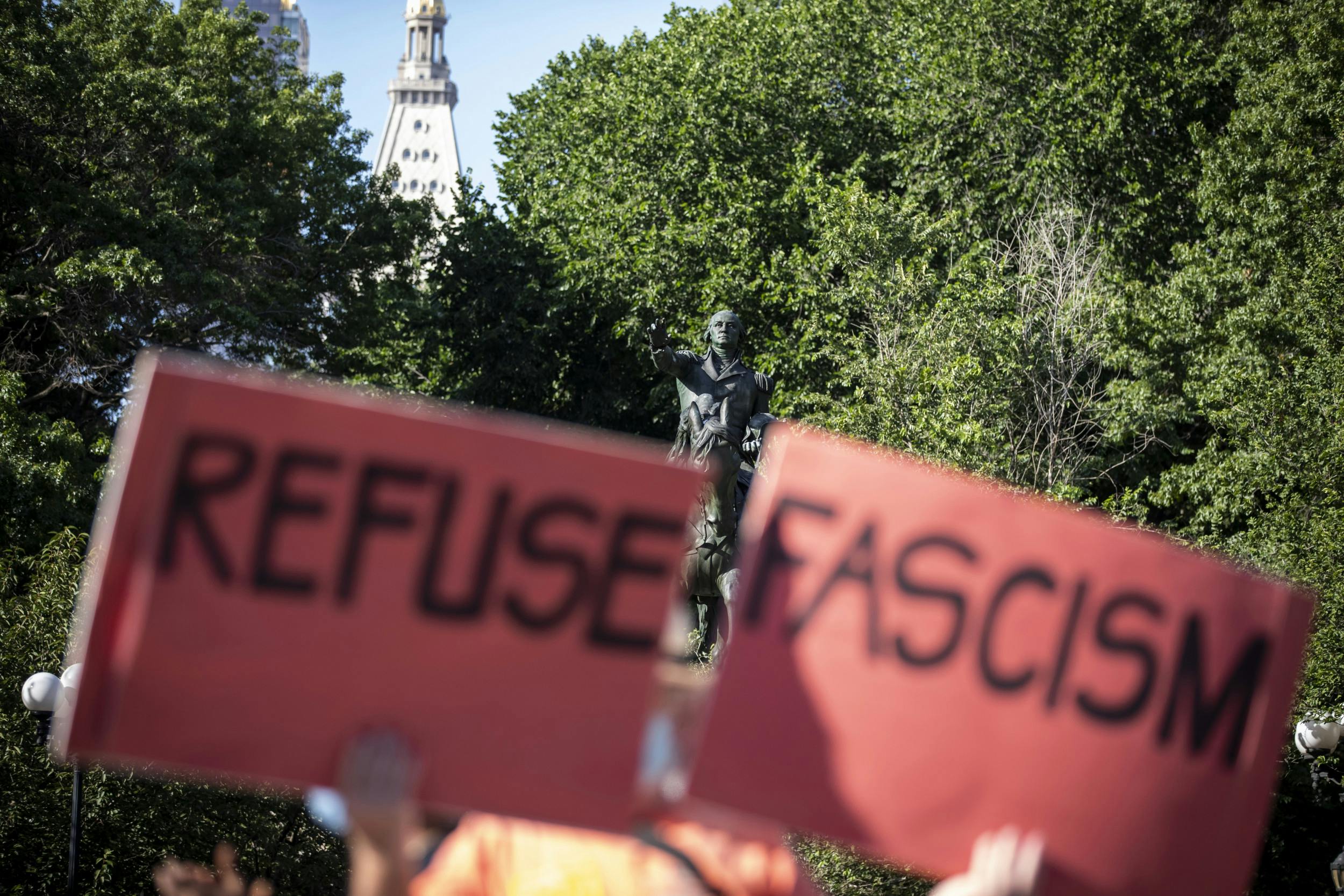 Protestschild auf einer Demo in 2021 in Washington. Eine Person, die nicht genauer zu erkennen ist, hält zwei Schilder hoch: Refuse Fascism