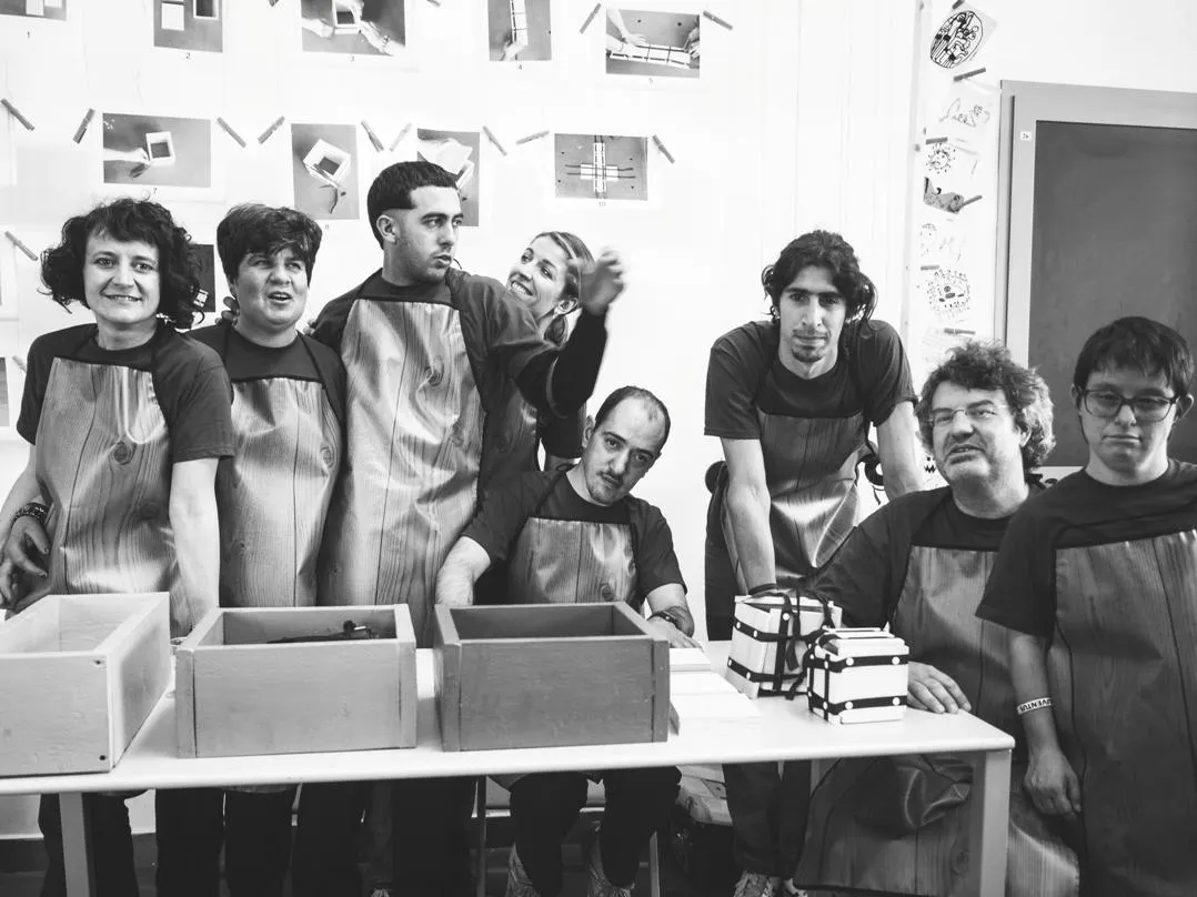 Foto in BN che mostra persone diversamente abili con grembiuli da artigiani