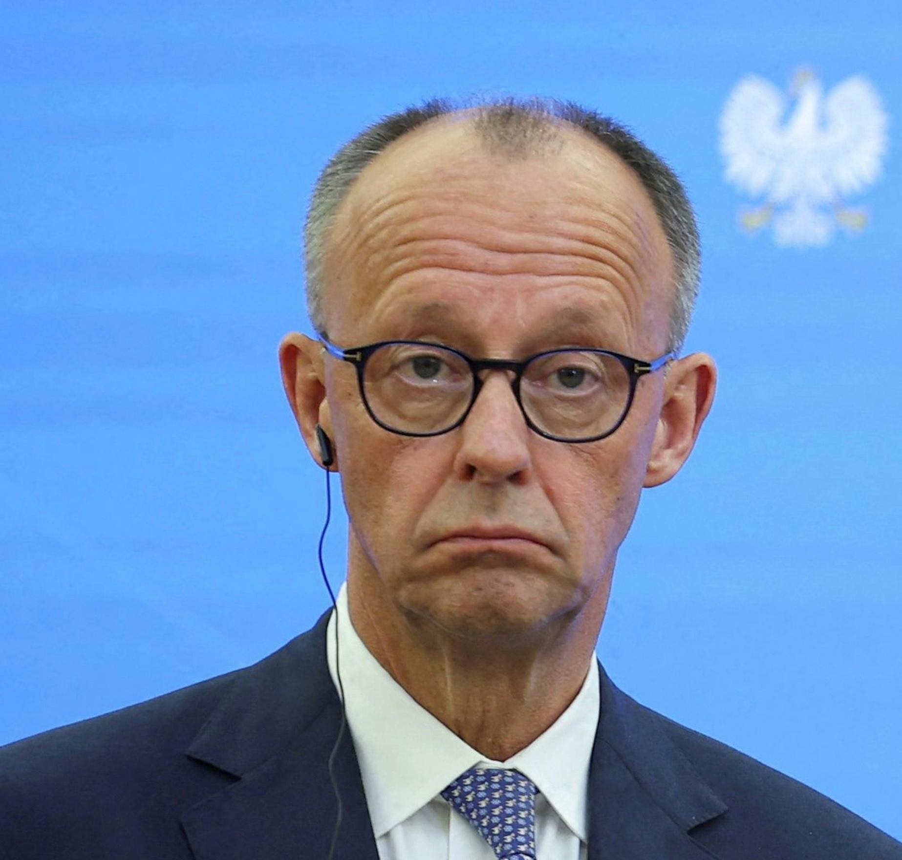 Friedrich Merz beim Antrittsbesuch in Polen, er schaut völlig leer und verdattert, die Stirn in Falten gelegt, die Mundwinkel nach unten gezogen