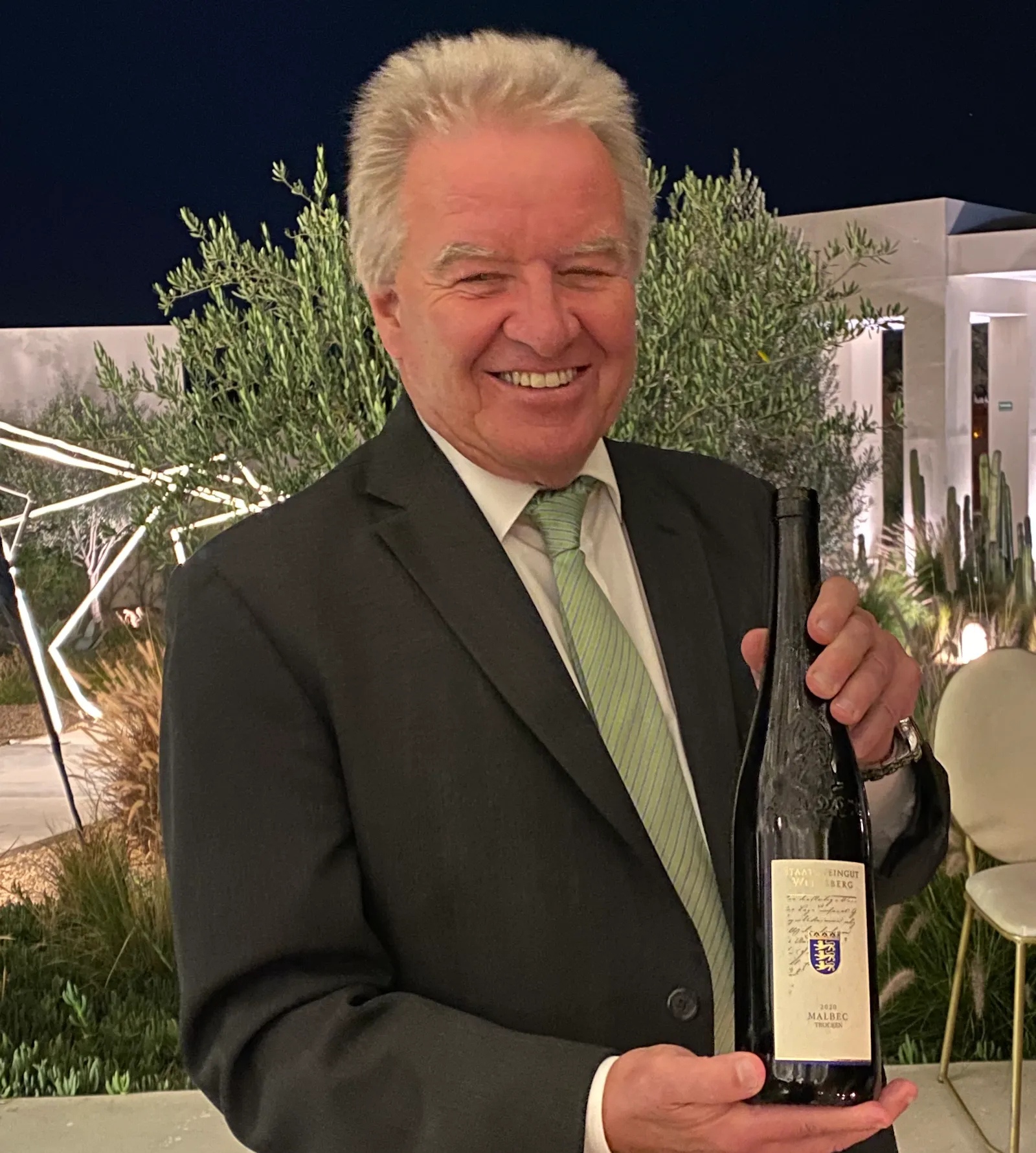 Franz Untersteller hält eine Weinflasche in der Hand