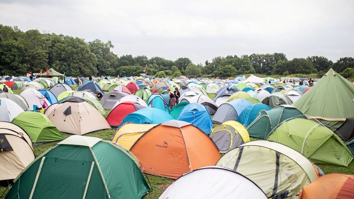 viele bunte Zelte auf einer Wiese, im Hintergrund Bäume