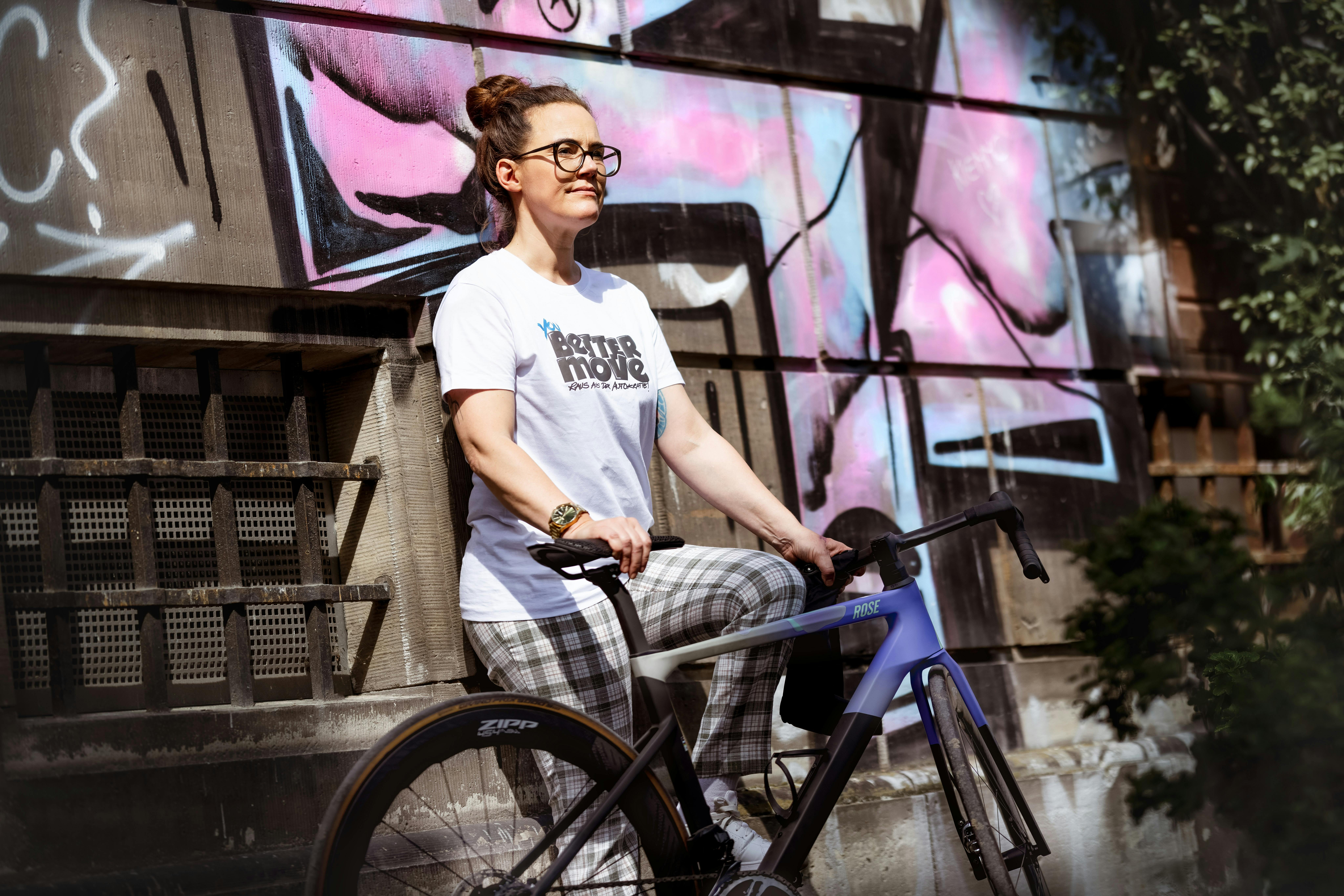 Ich trage das Tshirt, lehne an einer Mauer mit Graffitti und halte ein Fahrrad.